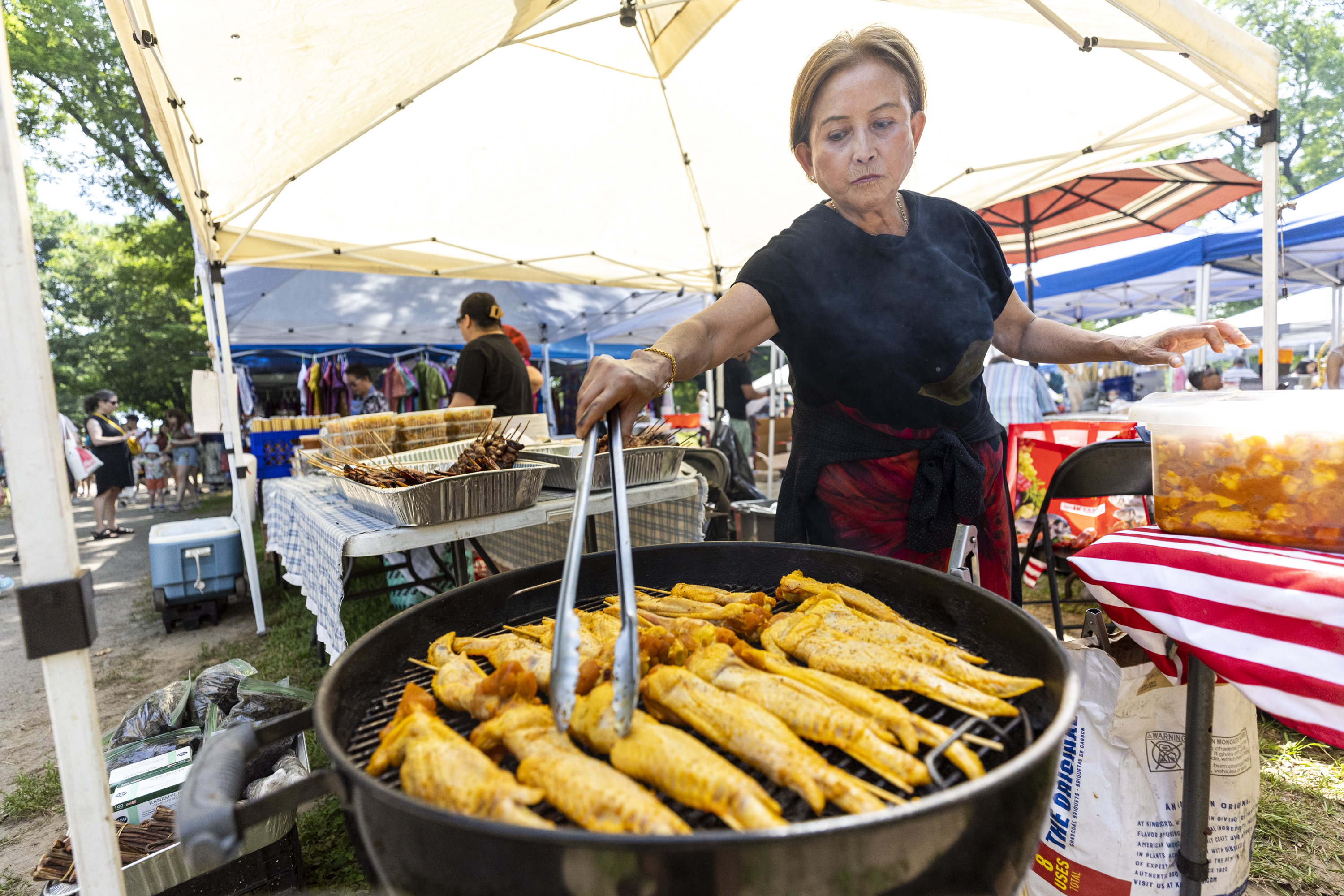 Hong Rattana, of Northeast Philadelphia, cooking some chicken wings on the grill at the Southeast Asian Market in FDR Park, in Philadelphia, Pa., on Saturday, May, 25, 2024.