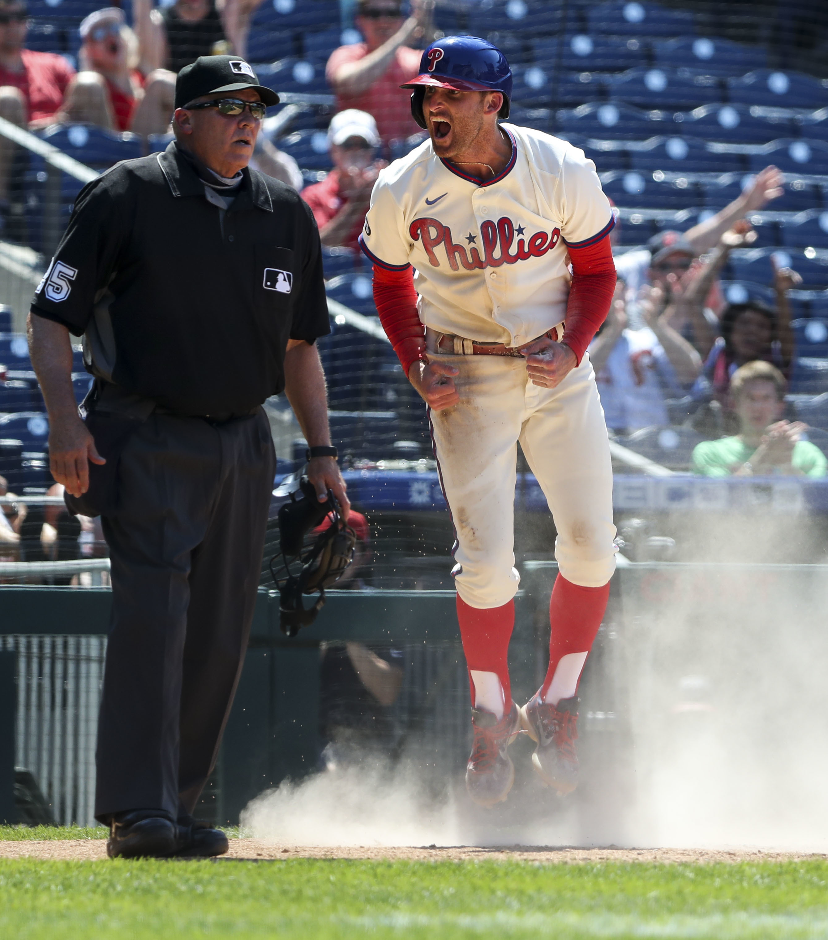 Philadelphia Phillies - Rhys Hoskins, wearing the cream Phillies uniform,  celebrating with the dugout after scoring a run.