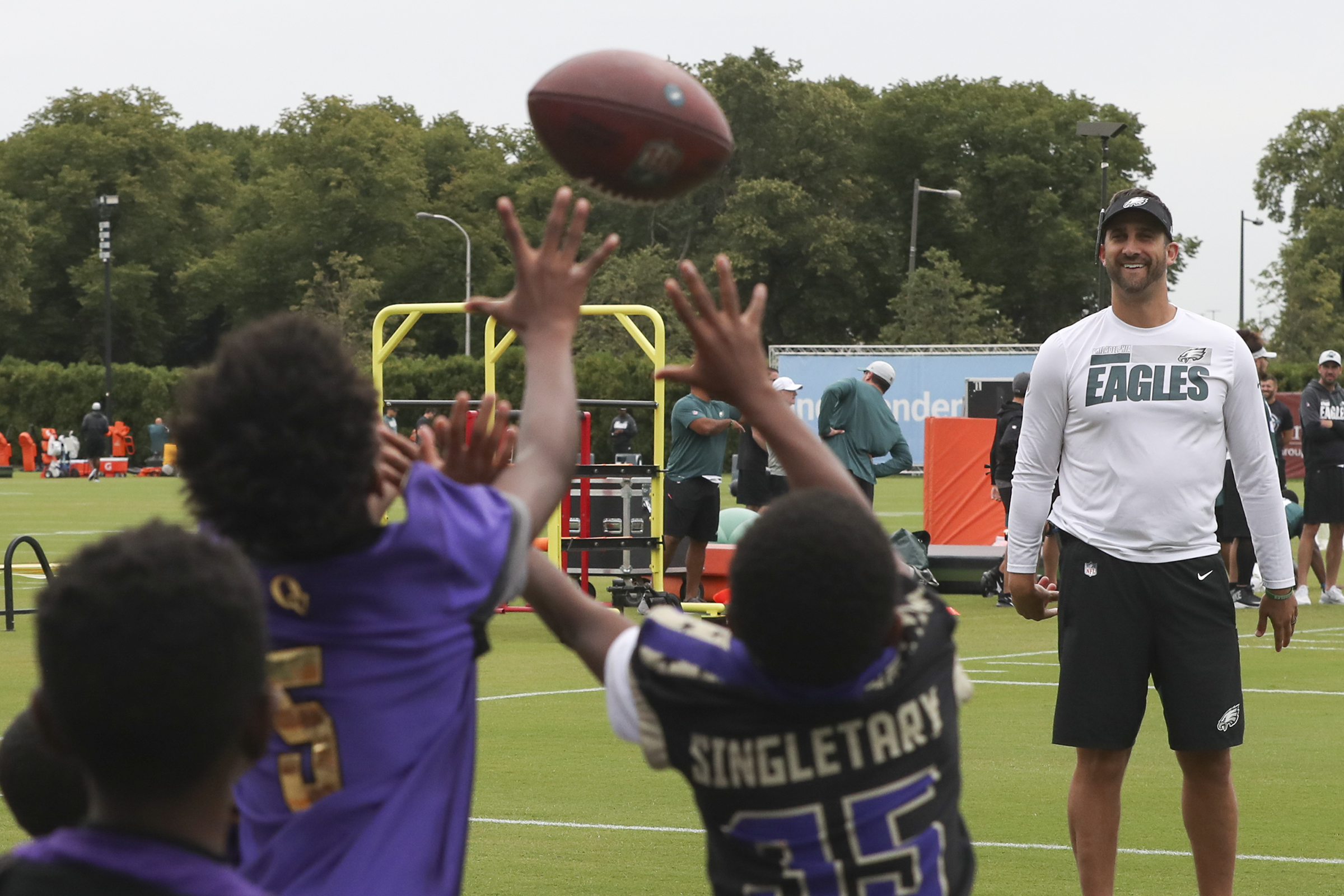 Eagles head coach Nick Sirianni tosses the ball to young football players with the Overbrook Monarchs before the start of training camp at the NovaCare Complex in South Philadelphia on Tuesday, Aug. 3, 2021.