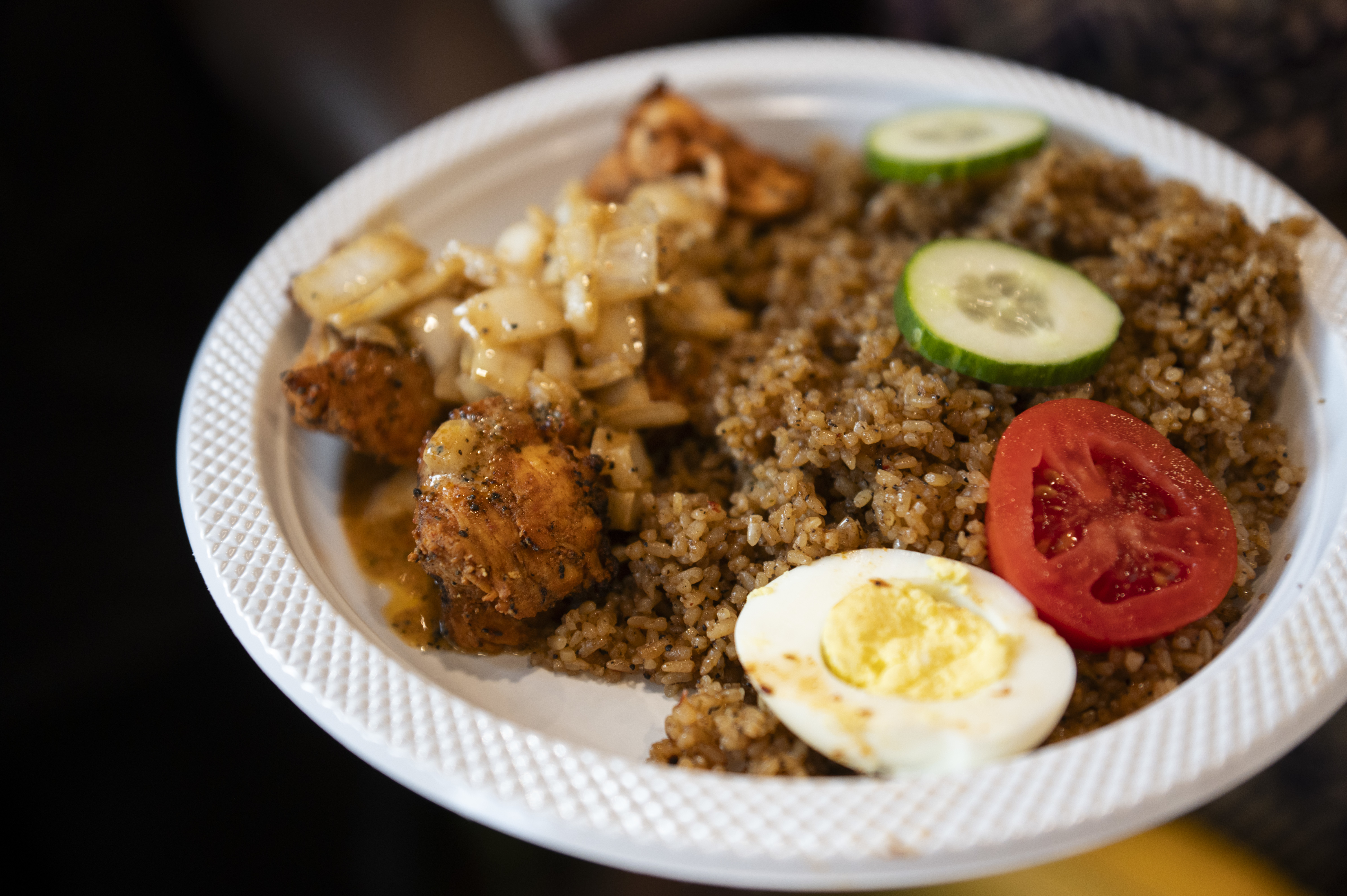 A plate of brown Jollof rice, chicken kebab, and plantains are served to patrons at West African restaurant Kilimandjaro during a grand reopening in a new space and location in West Philadelphia at 44th and Chestnut Streets on Sept. 12, 2024.