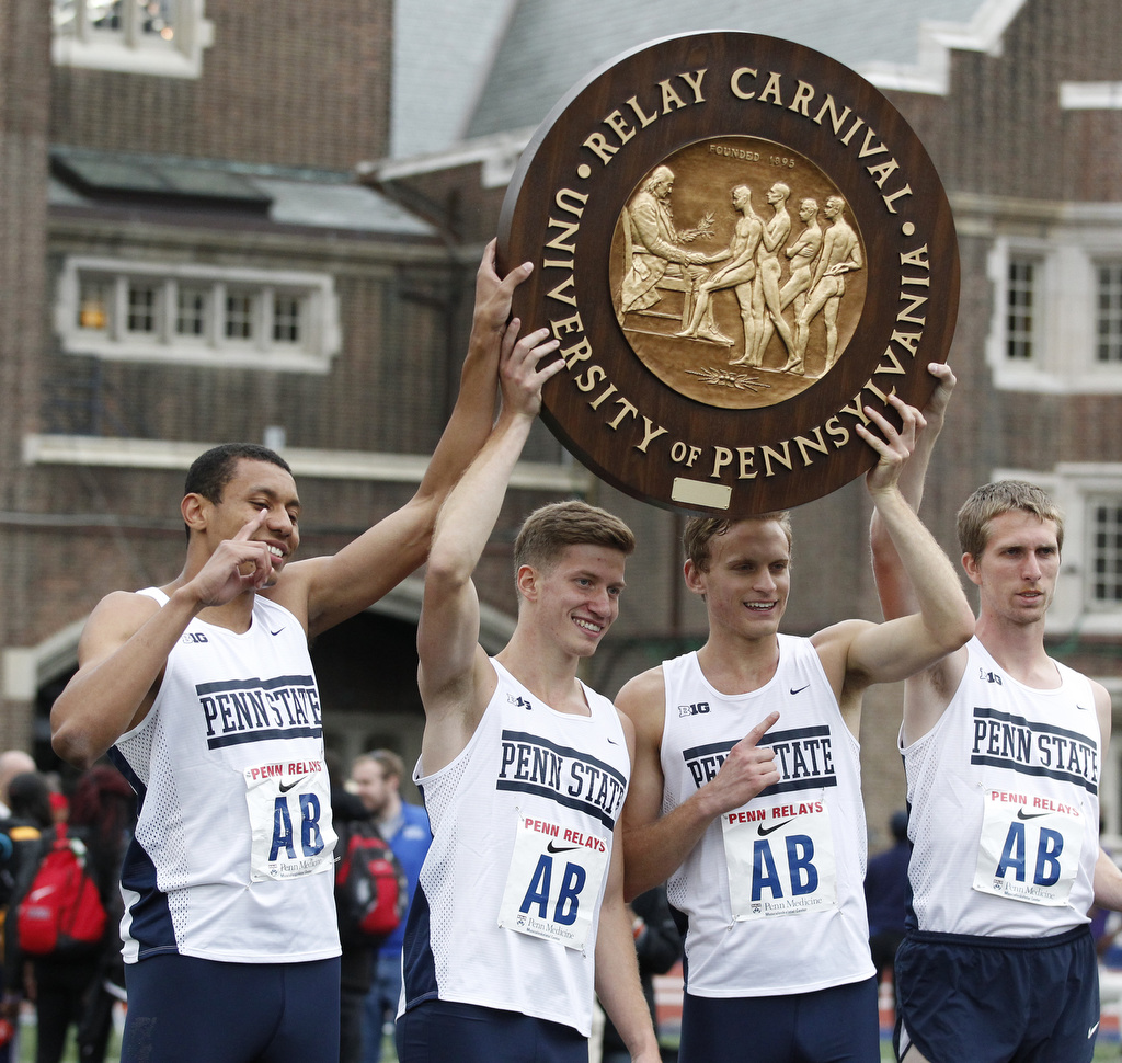 A Penn State relay team at the 2016 Penn Relays holds up the historic wheel  awarded to victors.