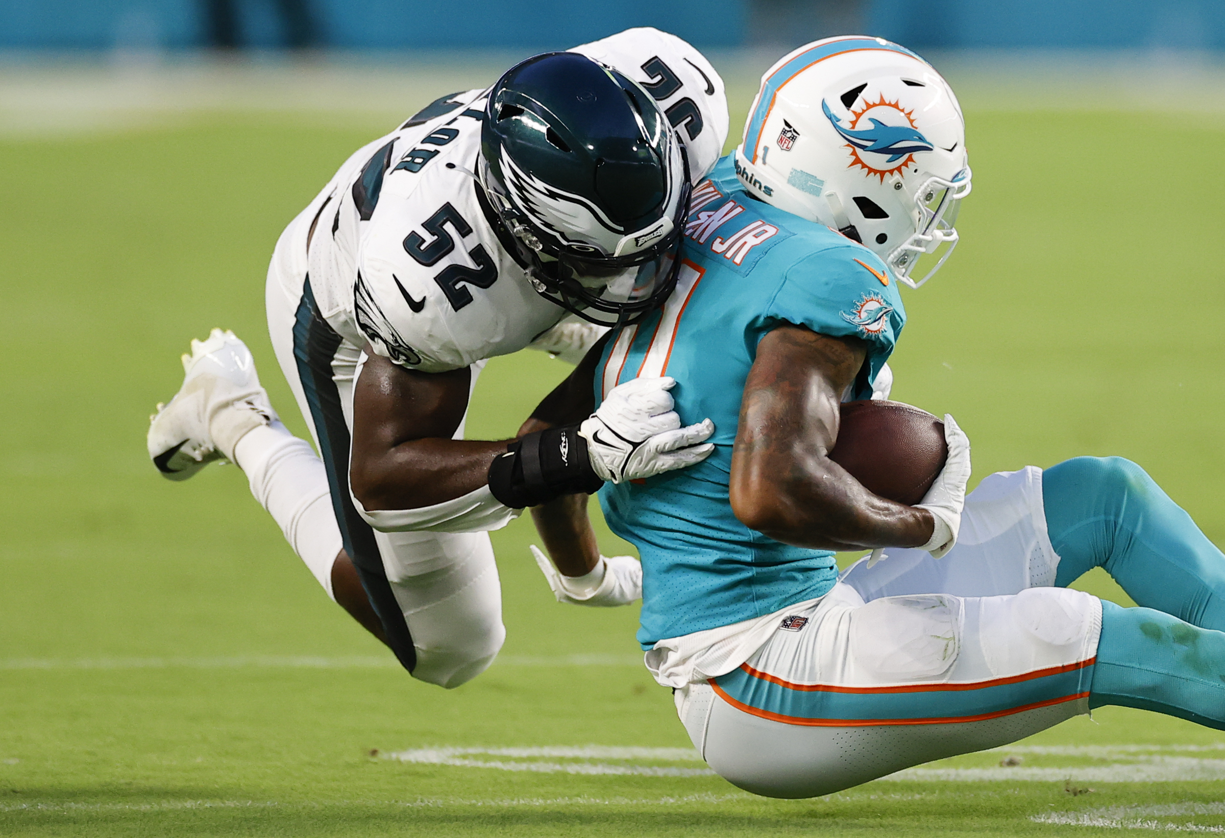 Philadelphia Eagles center Cameron Tom (66) recovers a fumble by  Philadelphia Eagles quarterback Reid Sinnett (not shown) and is tackled by Miami  Dolphins defensive tackle Niles Scott (70) and Miami Dolphins linebacker