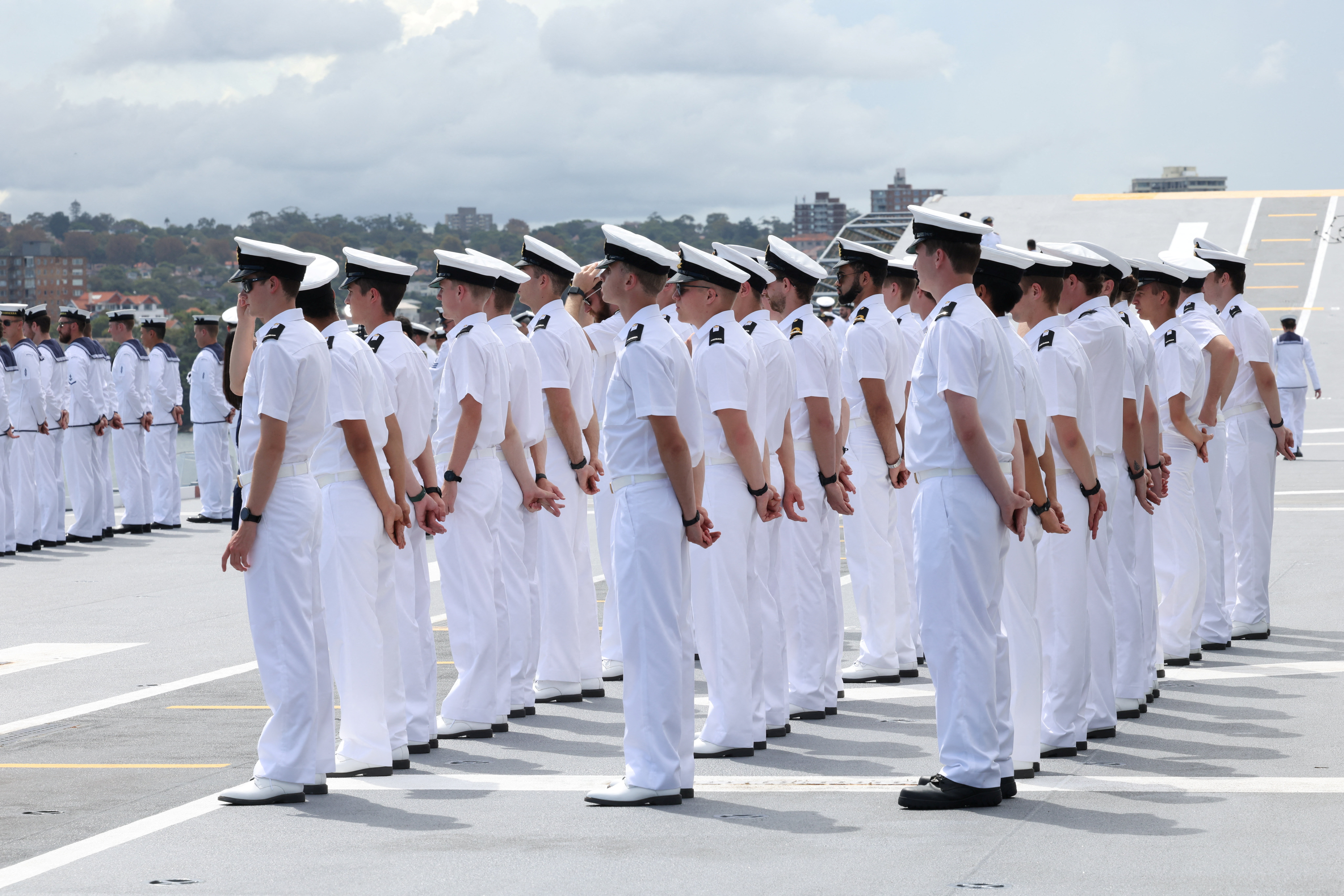 Sailors stand on board HMAS Canberra, facing the Opera House in Sydney, Australia, March 21, 2026.