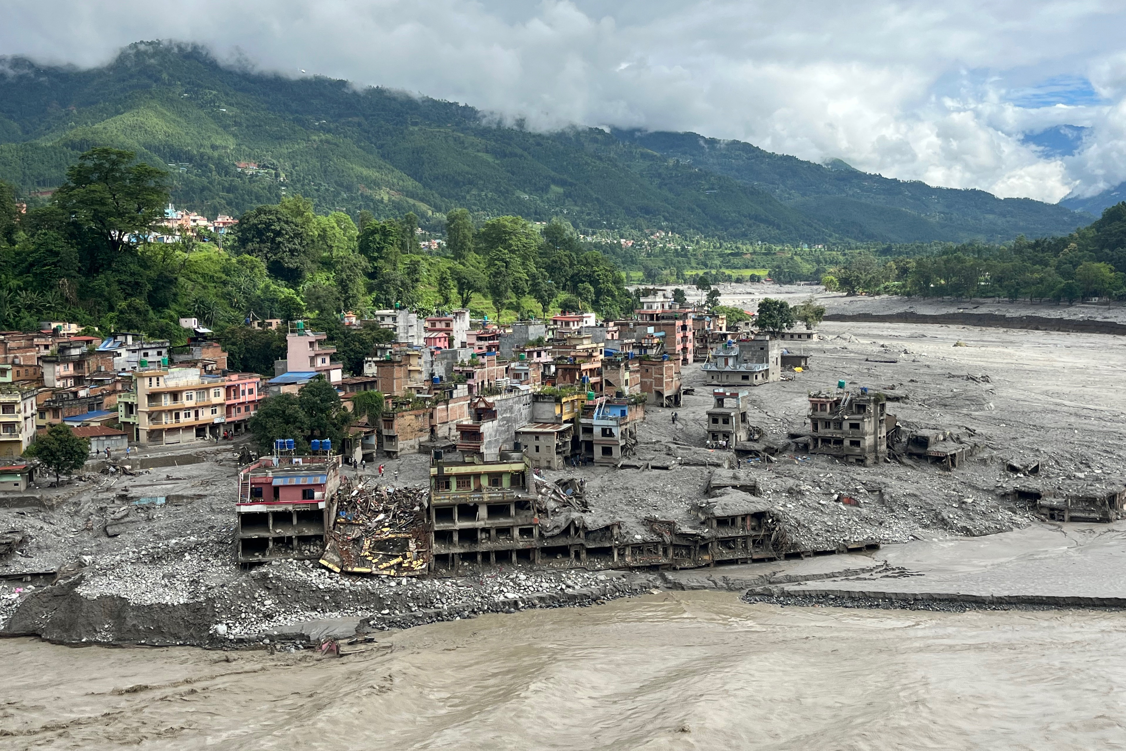 An aerial view shows a torrent of muddy water surging past houses and through the Trishuli River in the aftermath of flash floods at Trishuli Center in Nepal's Nuwakot district on Sept. 1, 2026.