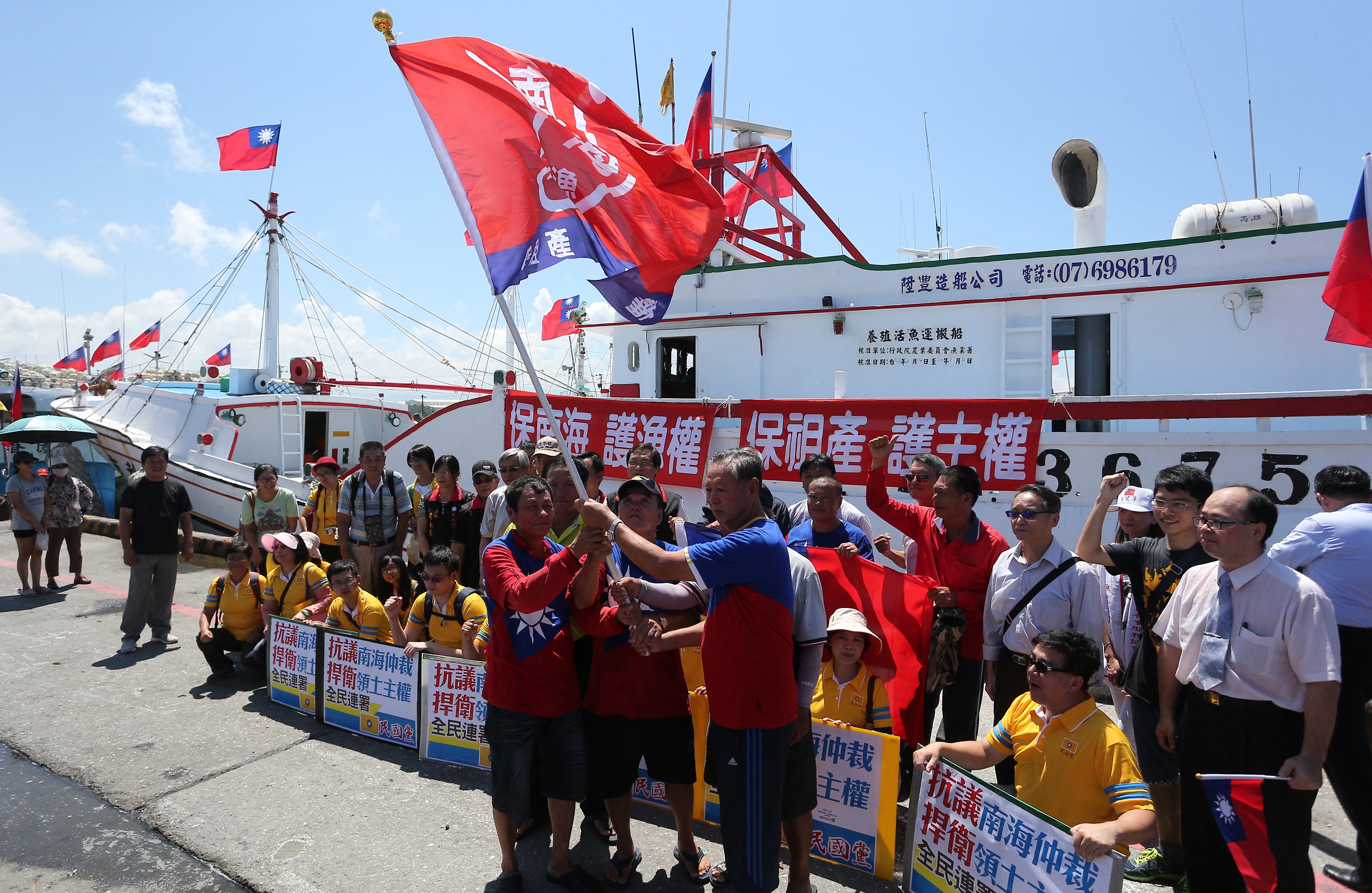 Taiwanese fishermen display flags and placards before departing to Taiping island, part of the disputed Spratly Islands chain in the South China Sea, at a fishing harbour in southern Pingtung on July 20, 2016.