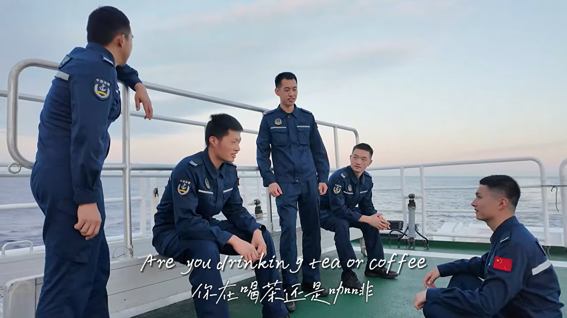A screenshot of the music video "I Miss You on the South China Sea" shows several men wearing China Coast Guard uniforms on the deck of a ship.