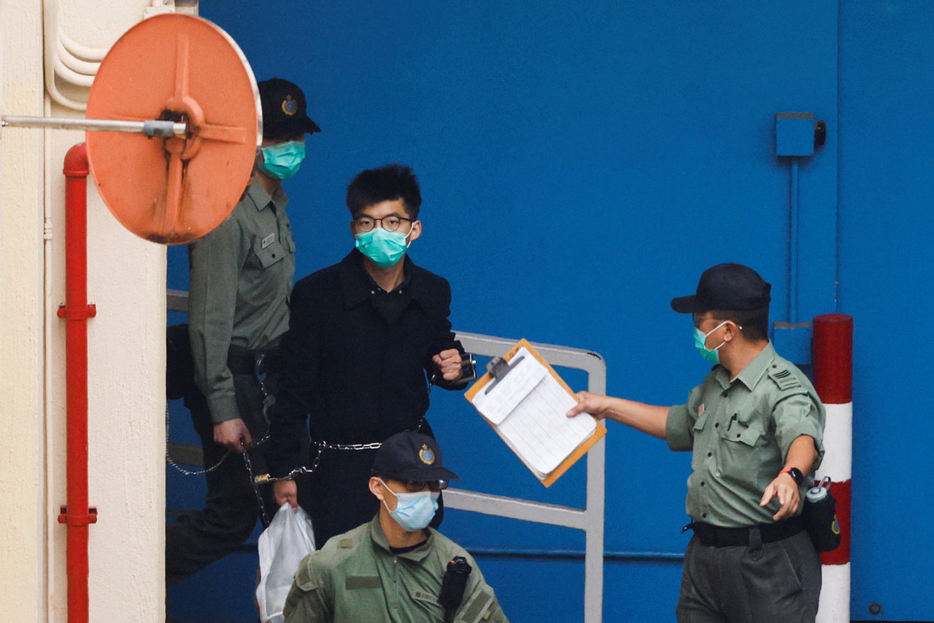 A March 4, 2021, photo shows pro-democracy activist Joshua Wong walking to a prison van to head to court in Hong Kong.