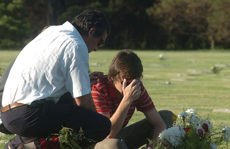 El viudo y el hijo de Nora frente a la tumba de la mujer, en Río Cuarto, al cumplirse un año del crimen.