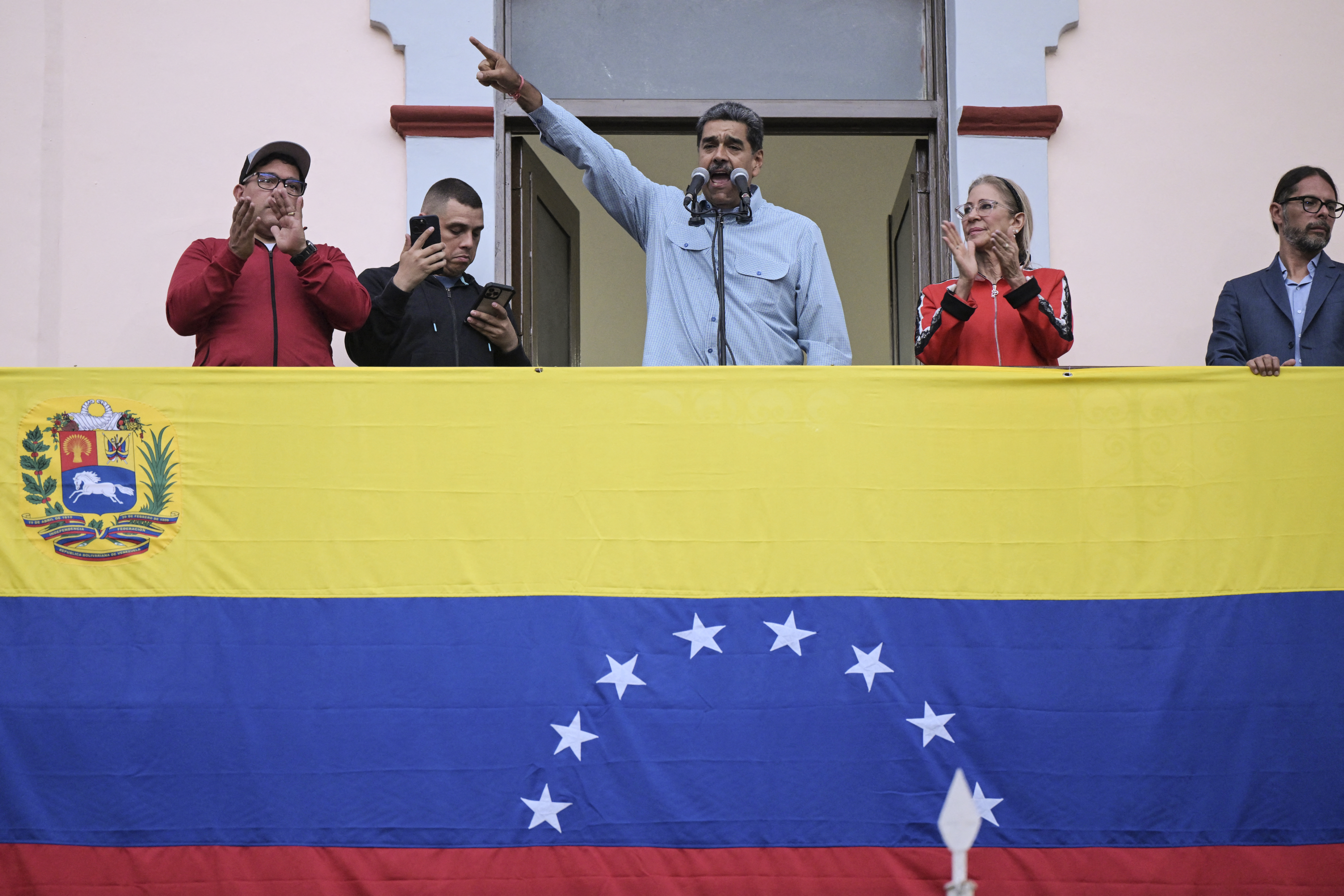 El presidente venezolano, Nicolás Maduro (C), acompañado por su esposa Cilia Flores (C-R), pronuncia un discurso ante sus seguidores durante una manifestación en el palacio presidencial de Miraflores en Caracas el 1 de agosto de 2024. El presidente de Venezuela, Nicolás Maduro, propuso este jueves "retomar" las negociaciones con Estados Unidos, país que no reconoció su reelección y apoya las acusaciones de fraude de la oposición. (Foto de Yuri CORTEZ / AFP)