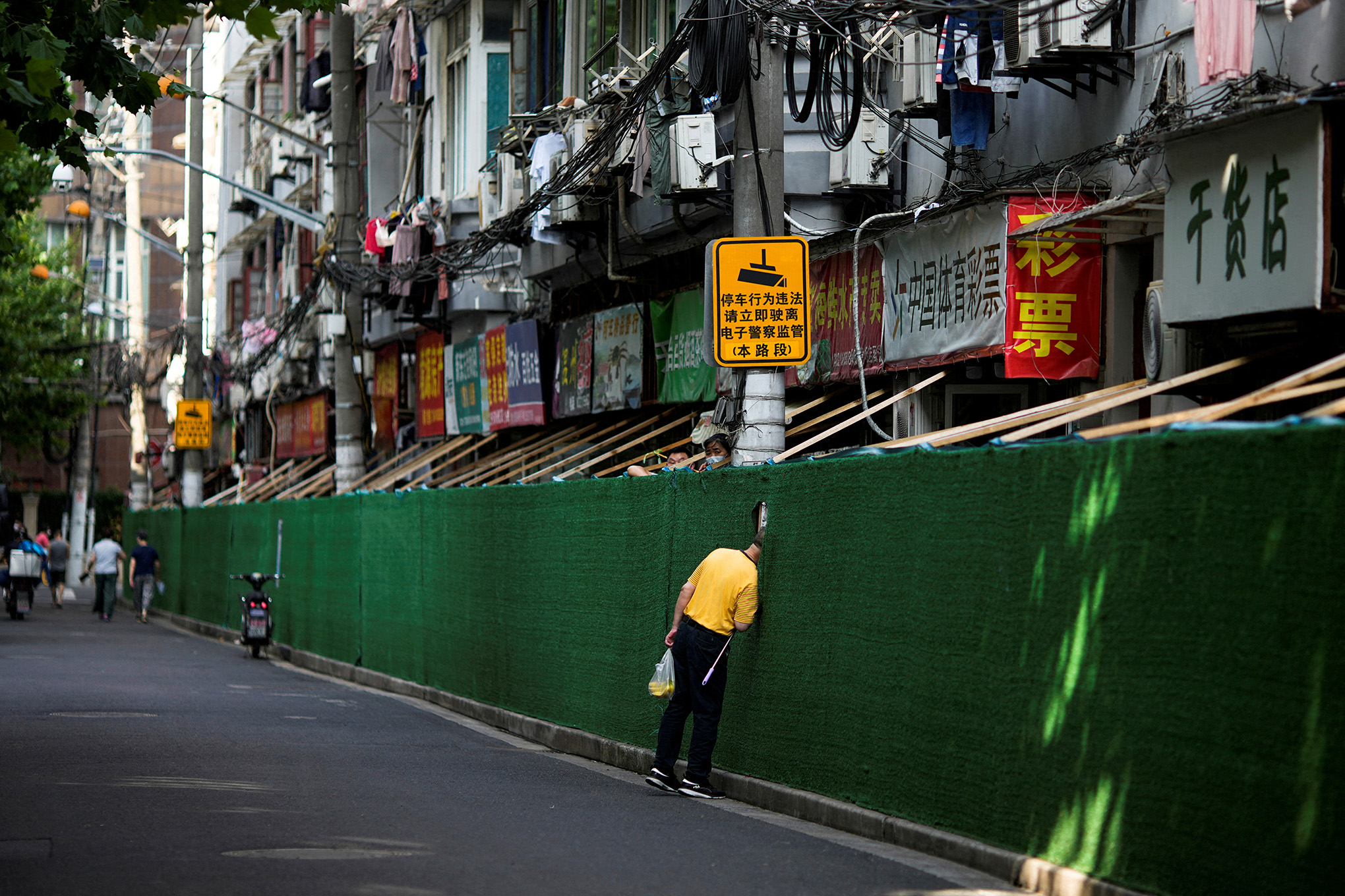 Un hombre mira a través de un hueco en una barrera en una zona residencial, después de que se levantara el bloqueo impuesto para frenar el brote de la enfermedad por coronavirus en Shanghái, China, el 7 de junio de 2022. Foto REUTERS/Aly Song 