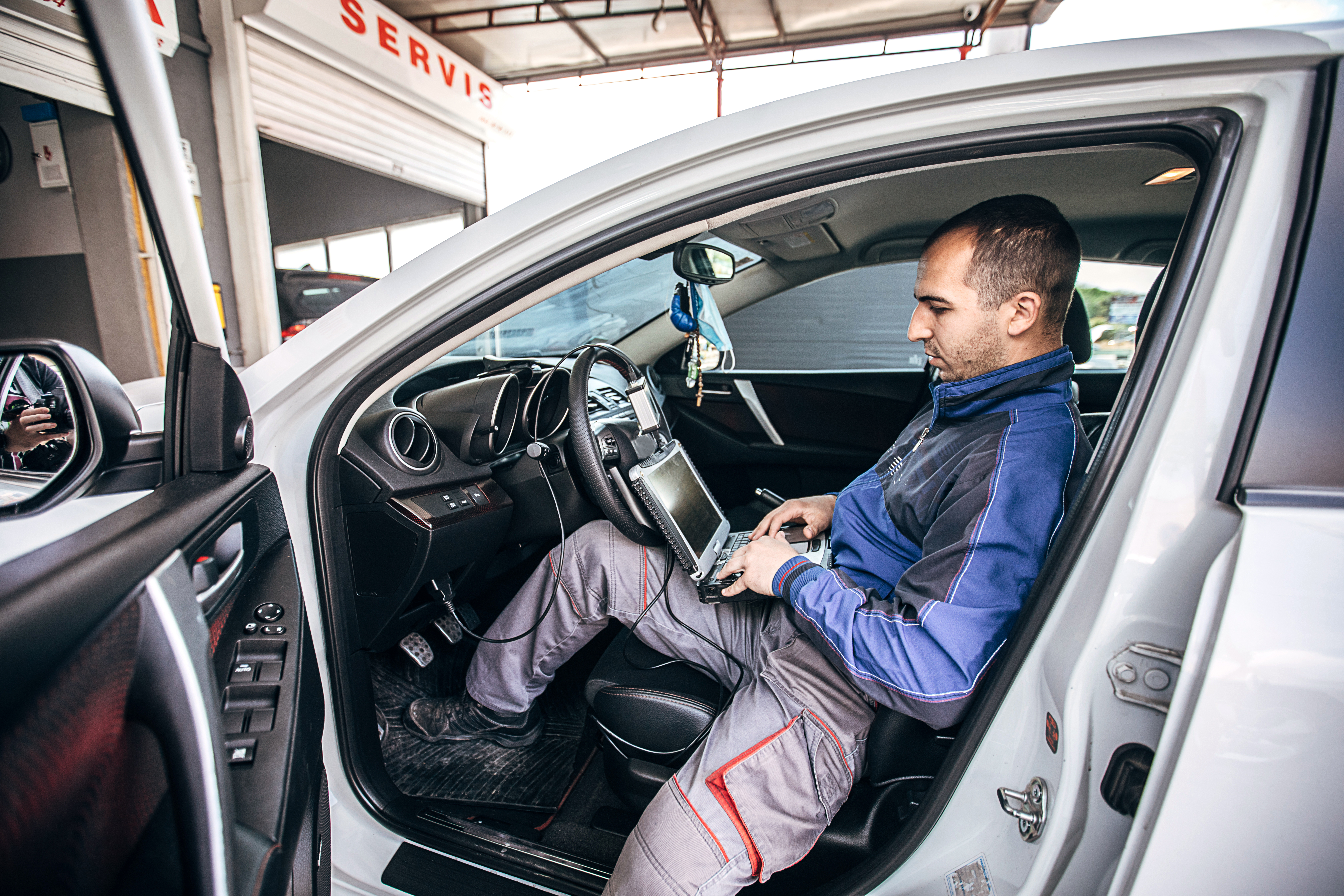 One young mechanic doing car diagnostic in auto repair shop.