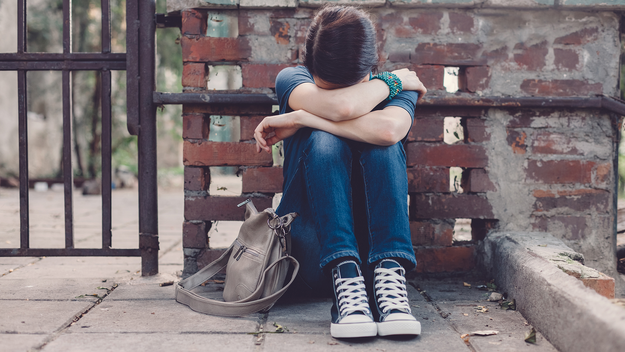 Niña llorando con la cabeza entre las manos sentada en el suelo