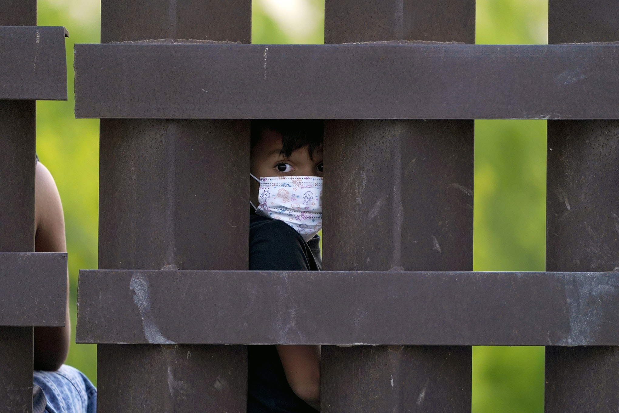 Un niño migrante mira a través del muro fronterizo entre Estados Unidos y México mientras un grupo es procesado y detenido cuando intentaban colarse a través de la frontera, en Abram-Perezville, Texas. Foto: AP / Julio Cortez.