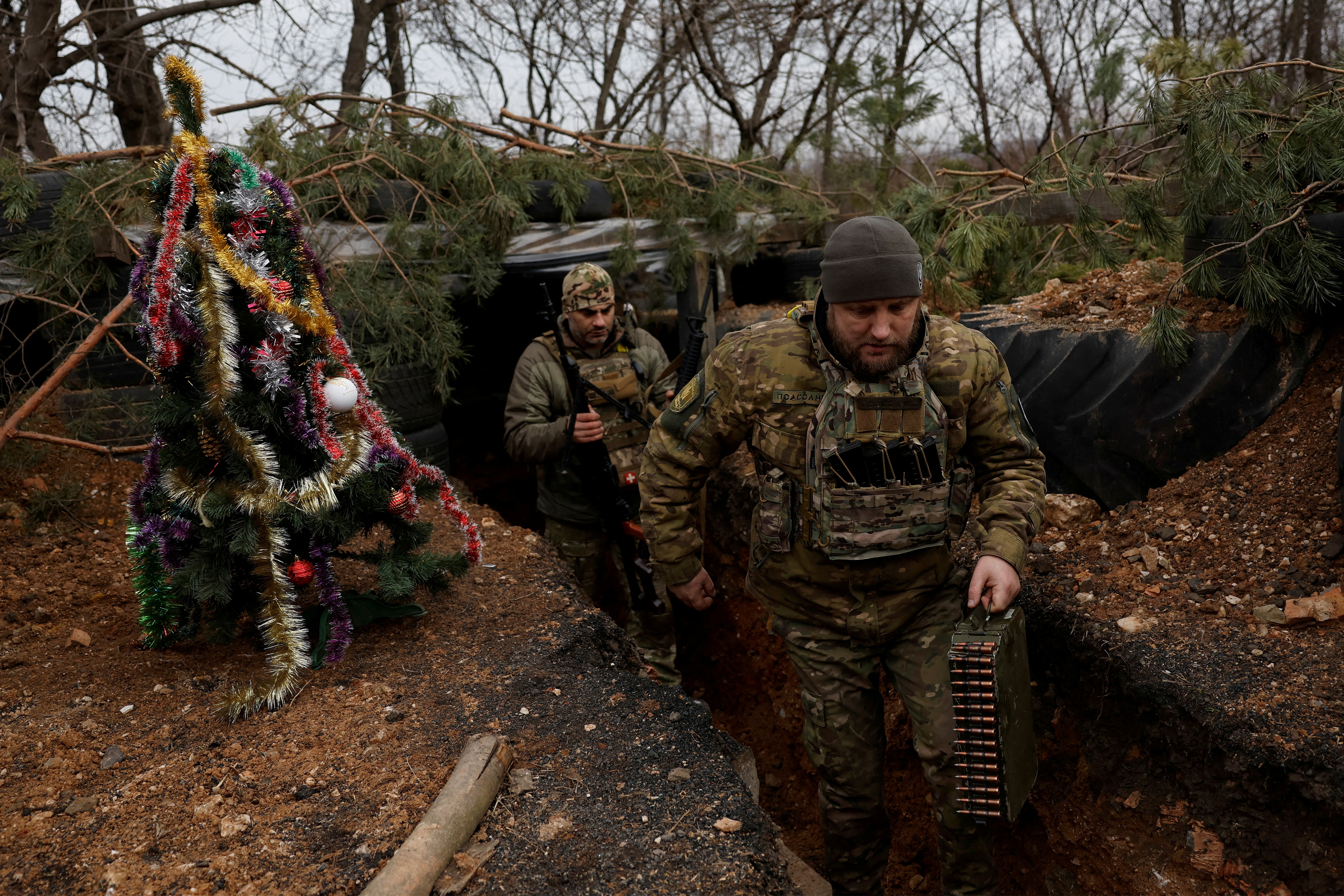 Militares ucranianos con el regimiento de policía de patrulla de tareas especiales Dnipro-1 Raphael Karapitian 45 y Roman Kapinus 39, camina con armas junto a un árbol de Navidad decorado en las trincheras en la línea del frente, mientras continúa el ataque de Rusia contra Ucrania , en Nochebuena en Bakhmut, Ucrania , 24 de diciembre de 2022. REUTERS/Clodagh Kilcoyne IMÁGENES TPX DEL DÍA