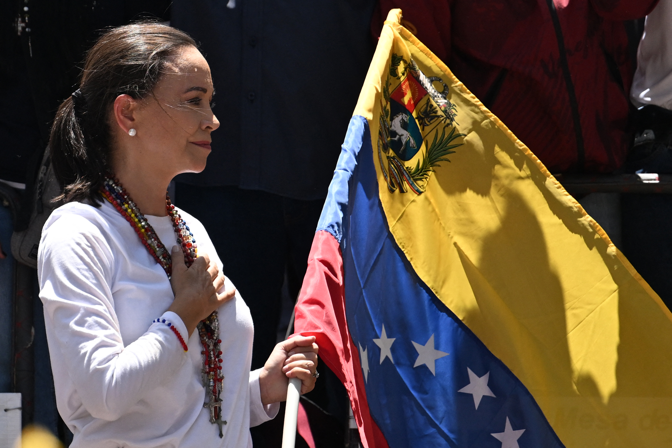 La líder de la oposición venezolana María Corina Machado sostiene una bandera nacional venezolana mientras hace gestos desde lo alto de un camión durante una manifestación para protestar por los resultados de las elecciones presidenciales, en Caracas el 3 de agosto de 2024. Venezuela se preparó para nuevas protestas después de que la disputada victoria electoral del presidente Nicolás Maduro fuera ratificado en la víspera, y un número creciente de naciones reconocieron a su rival de la oposición como el verdadero ganador. (Foto de Juan BARRETO/AFP)