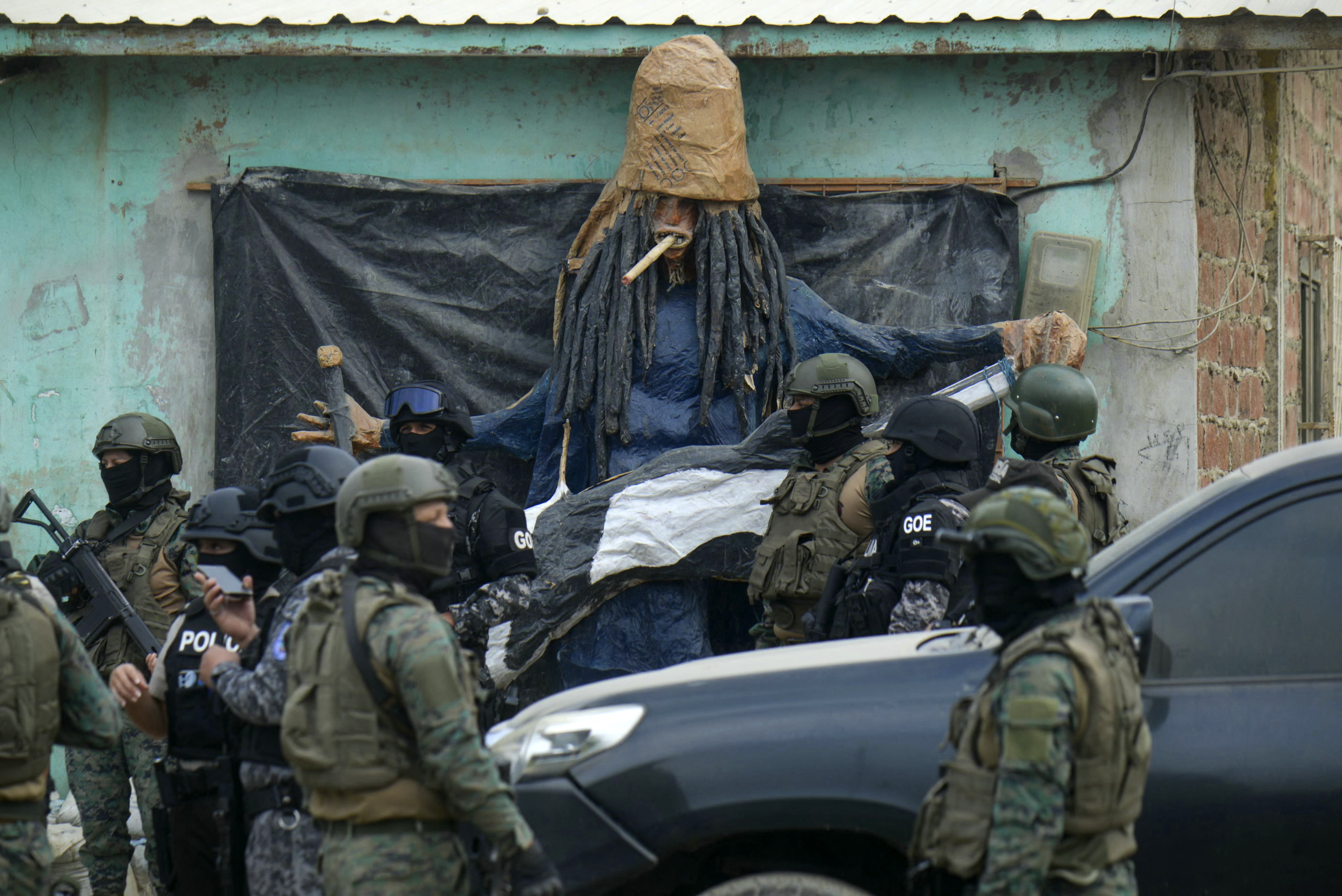 Personal de las fuerzas de seguridad pasa junto a un muñeco fabricado por miembros de la pandilla Latin King durante un operativo conjunto entre la policía nacional y las fuerzas armadas en el barrio "Una Sola Fuerza" en Durán, Ecuador, el 16 de octubre de 2024. (Foto de Gerardo MENOSCAL / AFP)