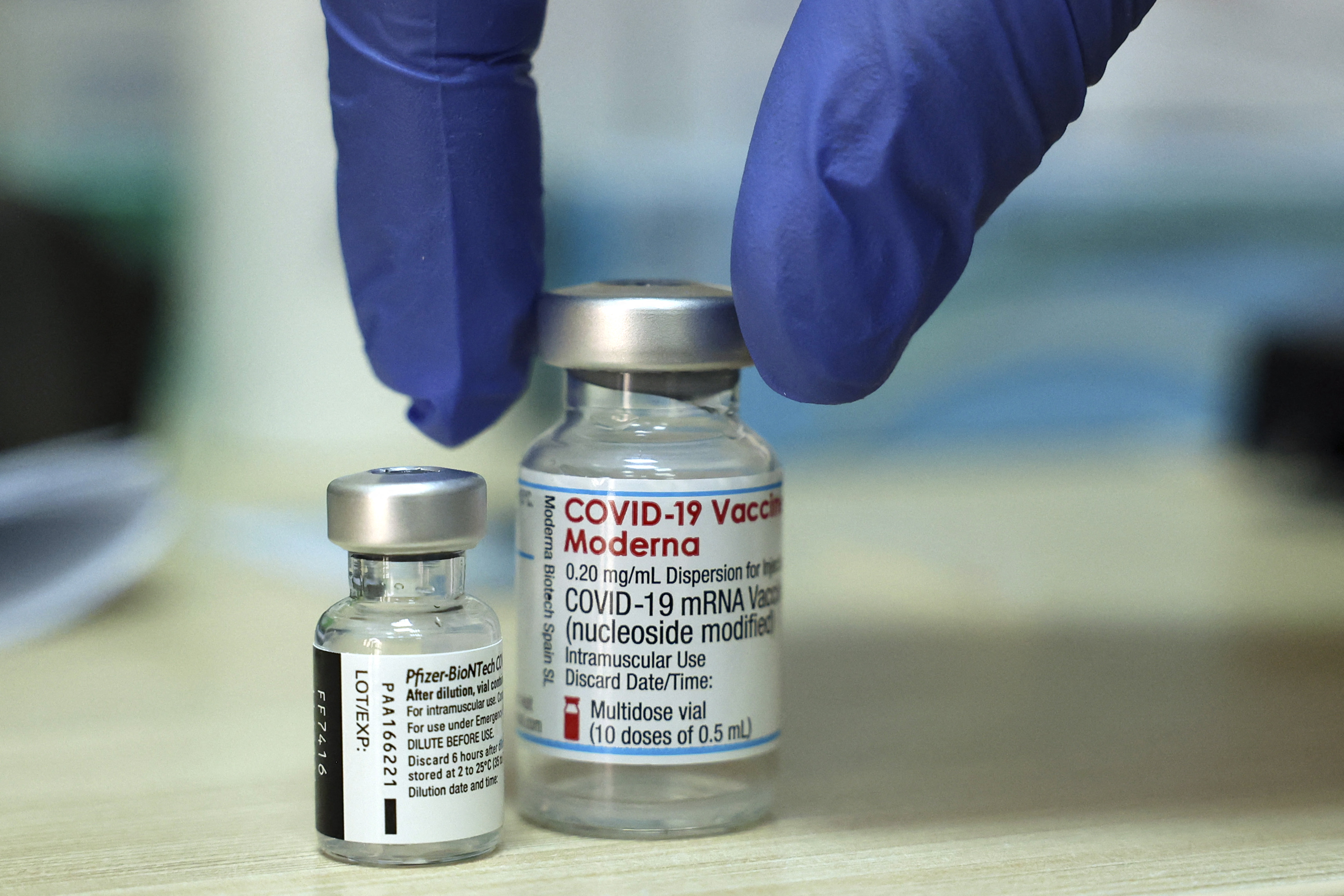 A medic places two vials of COVID-19 coronavirus vaccines (L to R): Pfizer-BioNTech and Moderna, on a table before administering doses at a Clalit Health Services Medical Centre in east Jerusalem on August 10, 2021. (Photo by HAZEM BADER / AFP)