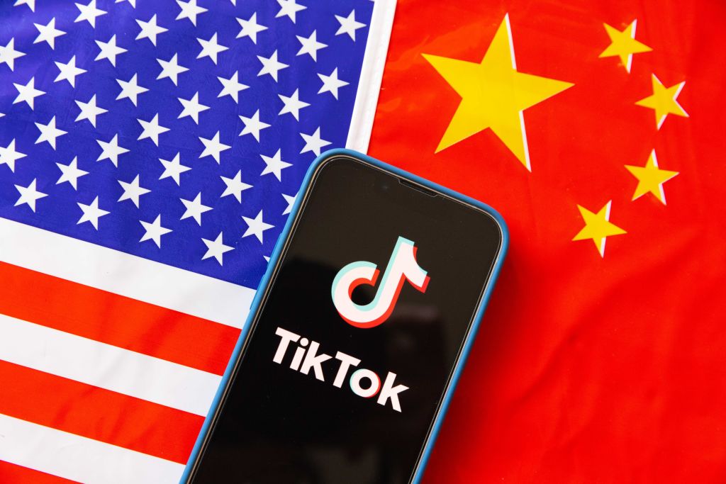 El logo de TikTok en medio de las banderas de Estados Unidos y de China (Photo Illustration by Stanislav Kogiku/SOPA Images/LightRocket via Getty Images)
