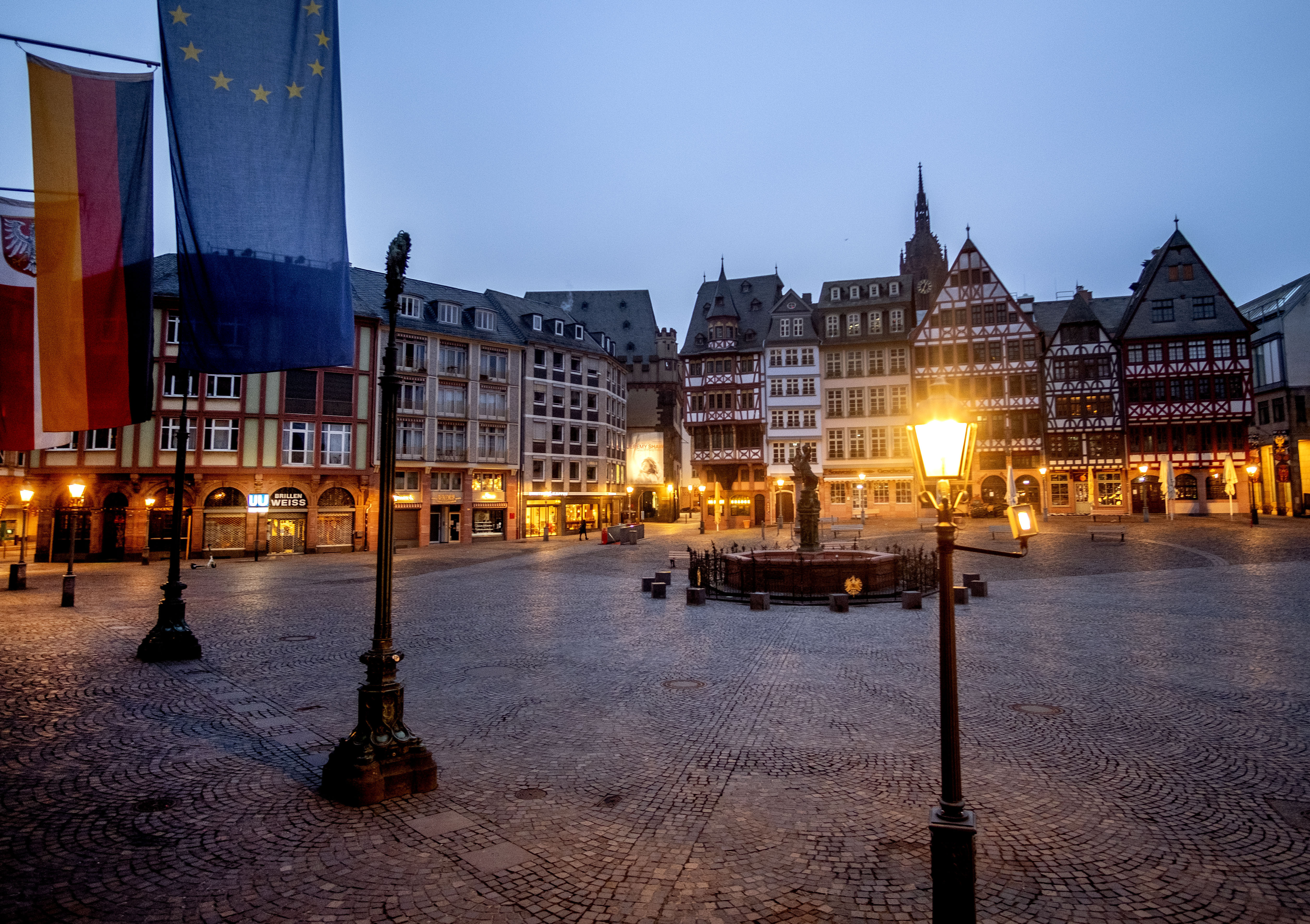 La plaza Roemerberg está vacía en Frankfurt, Alemania, la madrugada del martes 9 de marzo de 2021. Una bandera alemana y una europea están fijadas en el ayuntamiento de la izquierda. (Foto AP / Michael Probst)