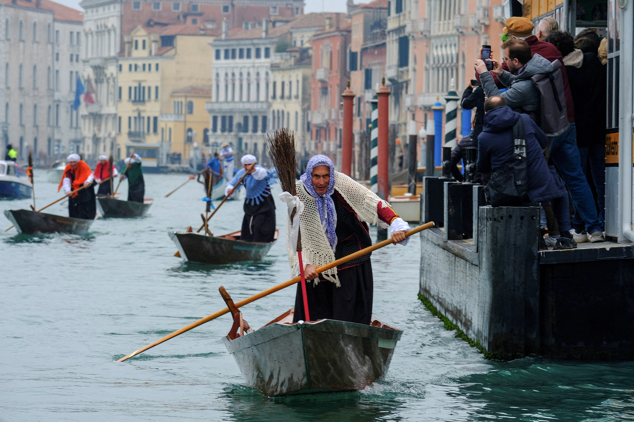 Hombres vestidos como "la Befana", una anciana imaginaria que se cree que lleva regalos a los niños durante el festival de la Epifanía, reman en botes por el Gran Canal de Venecia, Italia, 6 de enero de 2023.