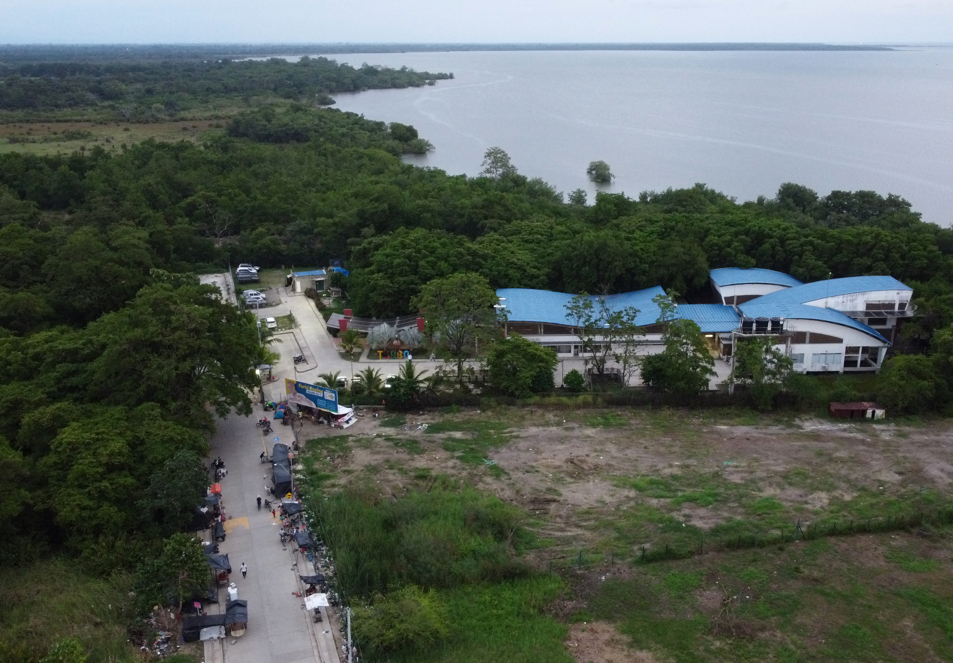 Vista aérea que muestra a migrantes varados, en su mayoría venezolanos, esperando en tiendas de campaña improvisadas en la ciudad portuaria de Turbo, Colombia, cerca del Tapón del Darién, una selva compartida por Colombia y Panamá, antes de continuar su viaje hacia Estados Unidos con la esperanza de una mejor situación. (Foto de Juan RESTREPO / AFP)