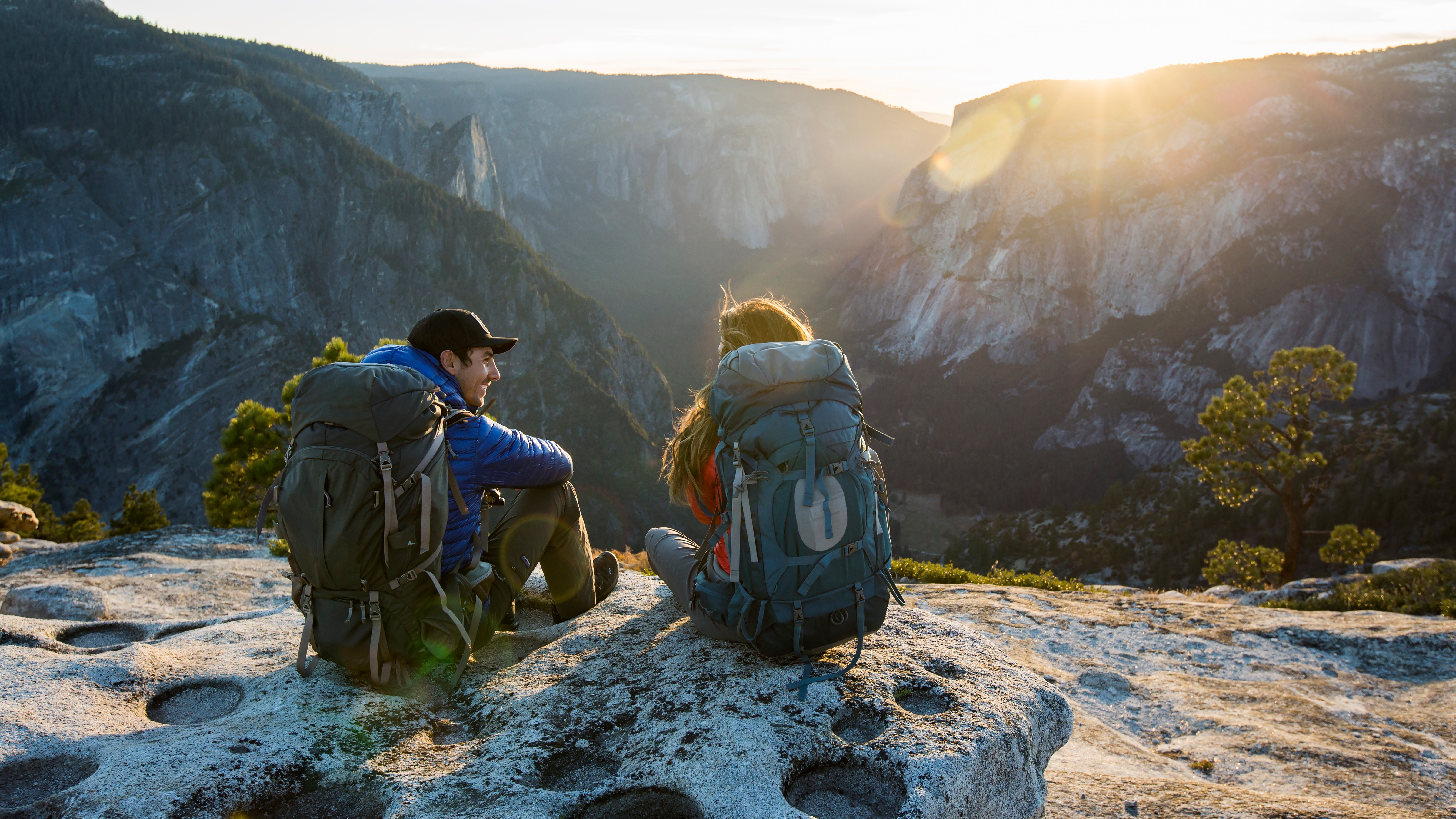 A couple sitting on a ledge while backpacking in Yosemite Valley.