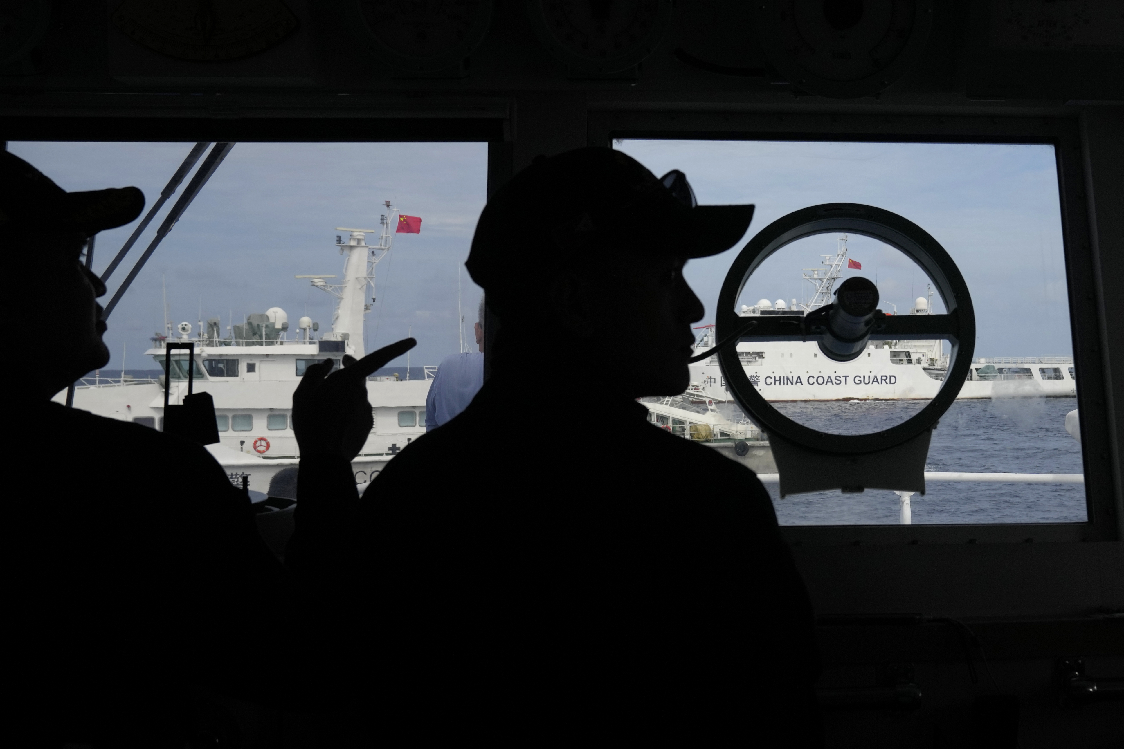 Philippine coast guard personnel on board BRP Cabra look at Chinese coast guard ships as the ships block their way off Second Thomas Shoal, locally known as Ayungin Shoal, at the disputed South China Sea during a rotation and resupply mission on Tuesday, Aug. 22, 2023. As a U.S. Navy plane circled overhead, two Philippine navy-manned boats manage to breach through a Chinese coast guard blockade in a dangerous confrontation in the disputed South China Sea and succeeded in delivering food and other supplies to Filipino forces guarding a contested shoal on board BRP Sierra Madre. (AP Photo/Aaron Favila)