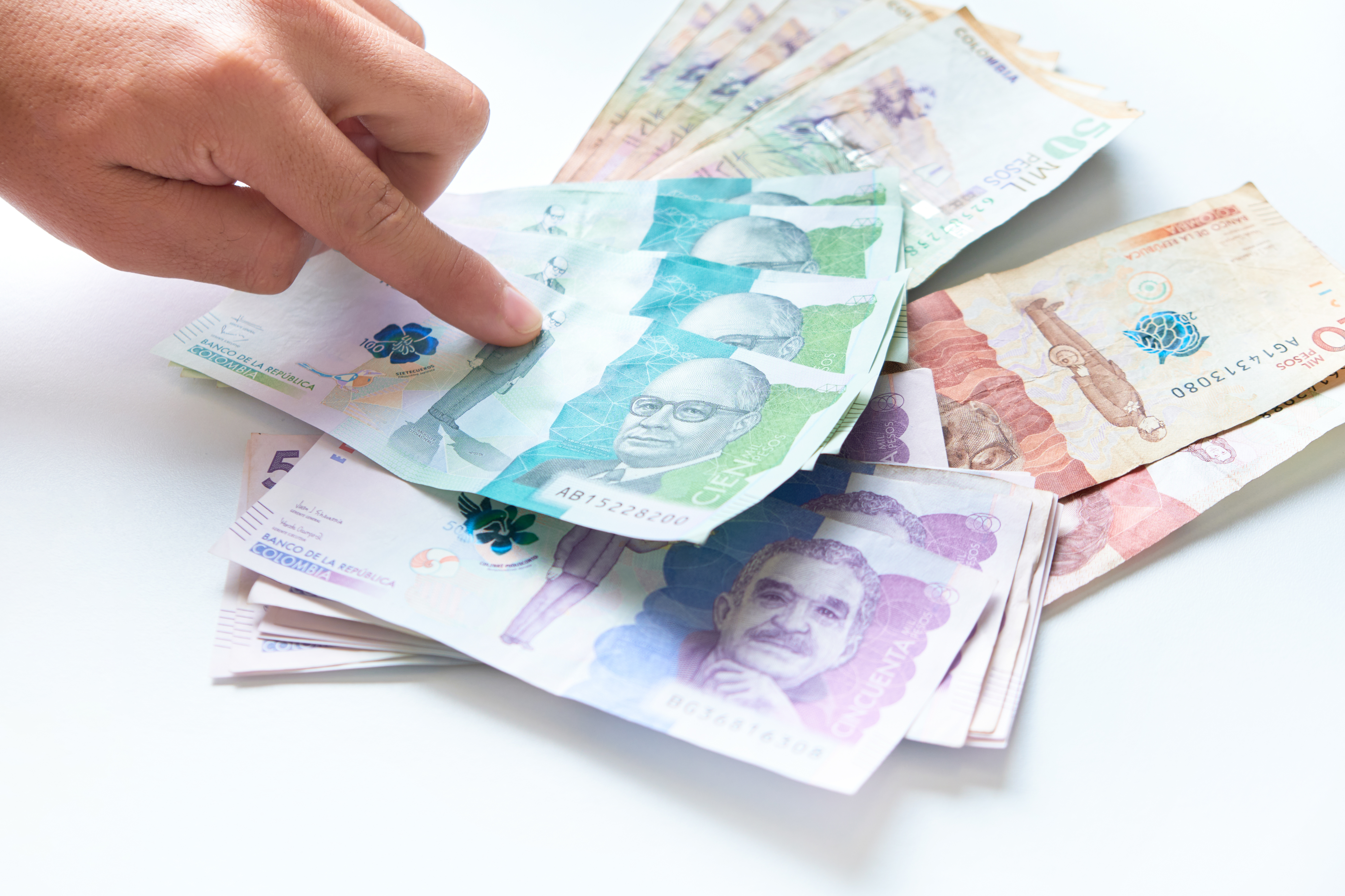 Manos rebiendo dinero billetes fondo blanco     Dinero Colombia pesos Colombianos