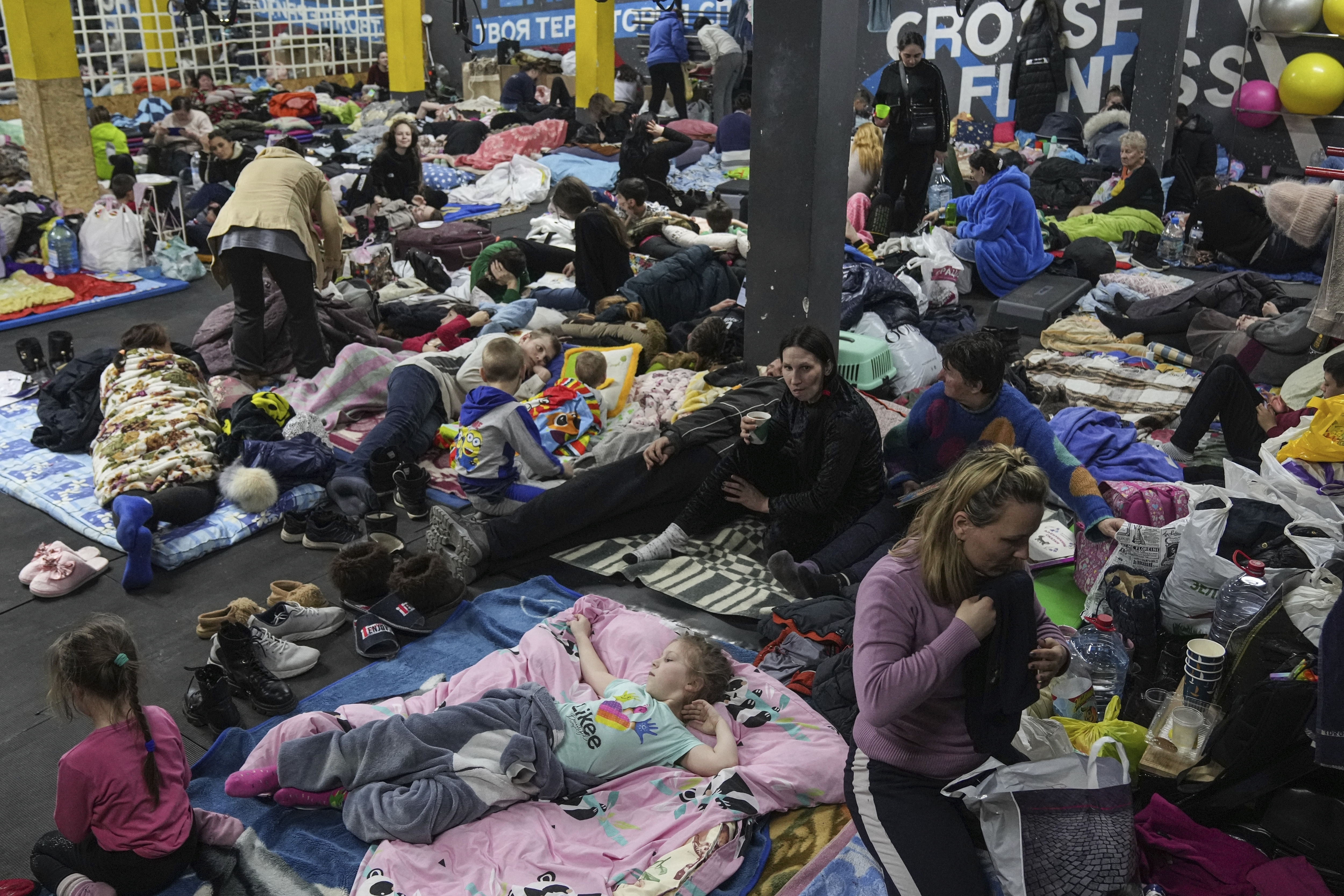Centro deportivo usado como refugio atestado de personas que le escapan a los bombardeos rusos en Mariupol, Ucrania, el 27 de febrero del 2022. (AP Photo/Evgeniy Maloletka)