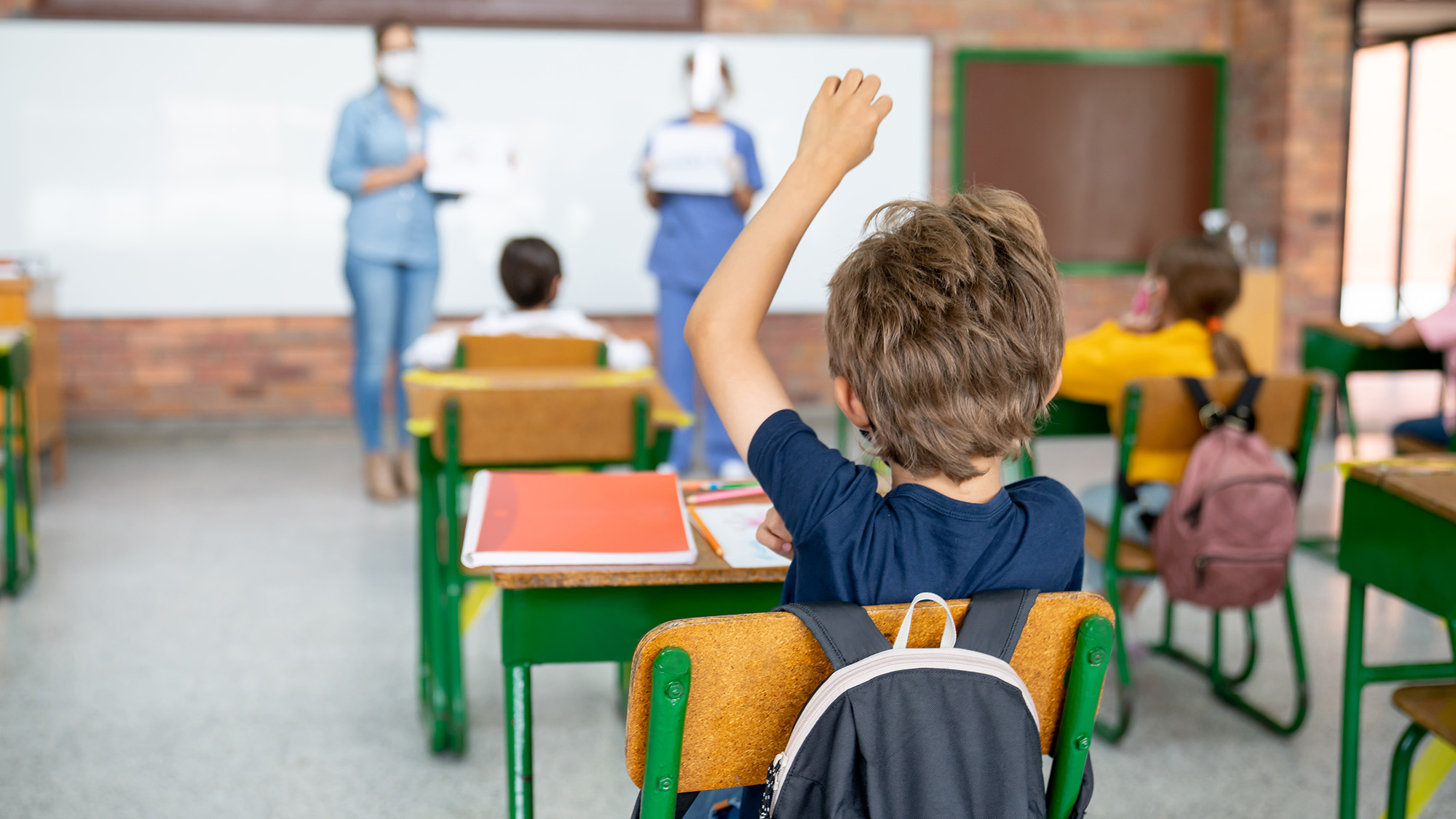 Niño en la escuela haciendo preguntas a una enfermera sobre la pandemia de COVID-19 - conceptos educativos