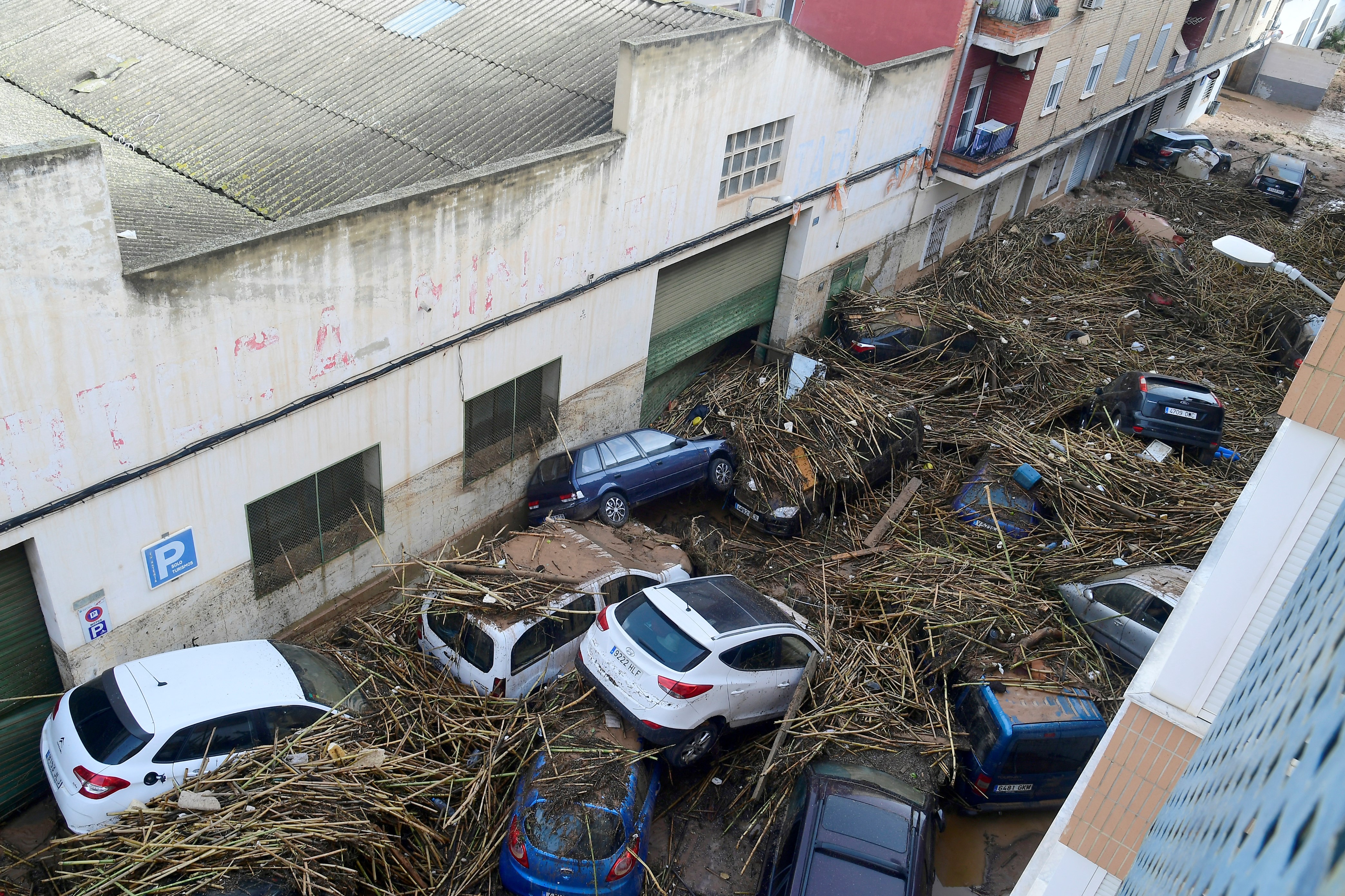 Family members walk in a street covered in mud in a flooded area in Picanya, near Valencia, eastern Spain, on October 30, 2024. Floods triggered by torrential rains in Spain's eastern Valencia region has left 51 people dead, rescue services said on October 30. (Photo by Jose Jordan / AFP)