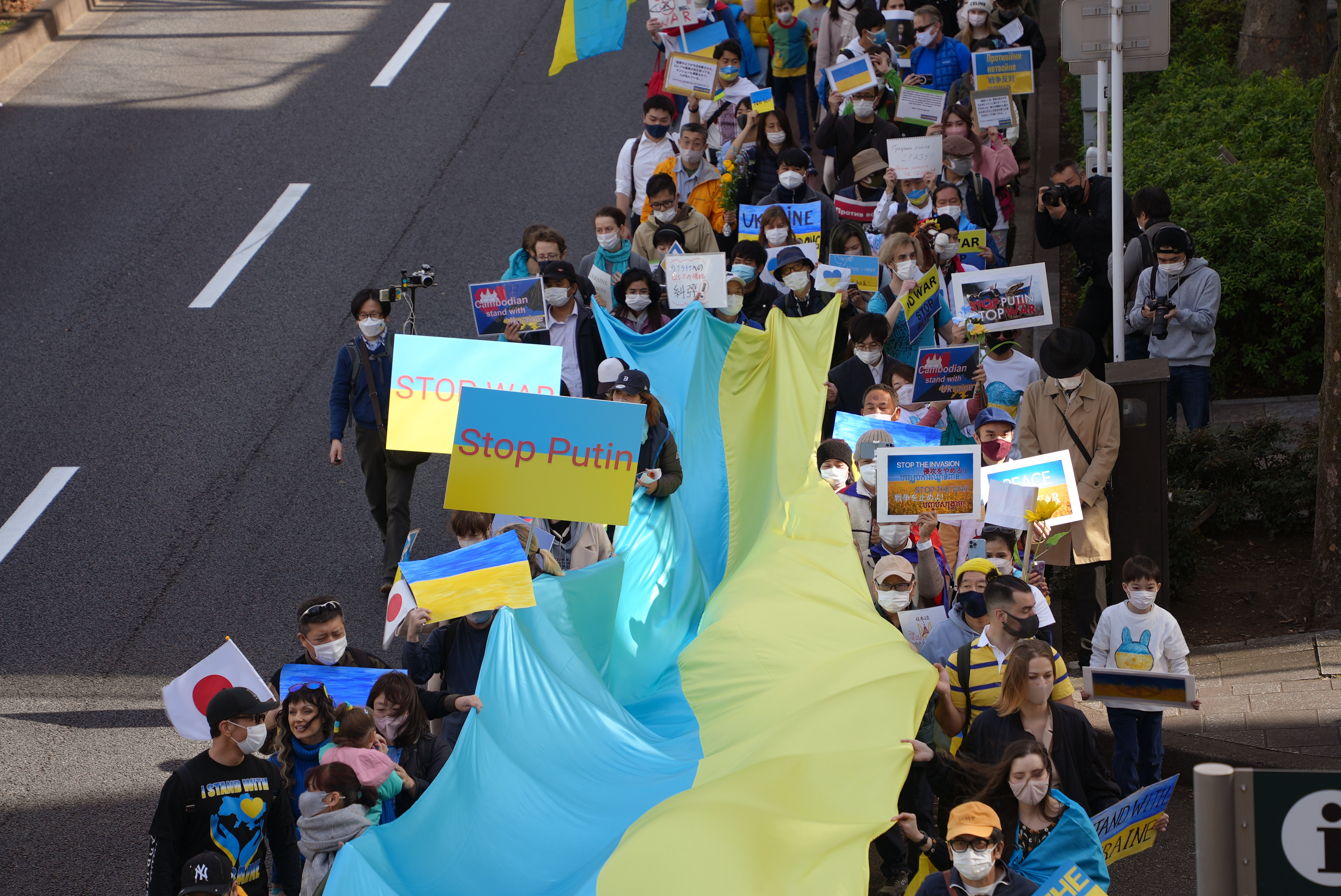 Los manifestantes sostienen una enorme bandera y pancartas durante una marcha que denuncia la invasión rusa de Ucrania en Tokio (AP Photo/Chisato Tanaka)