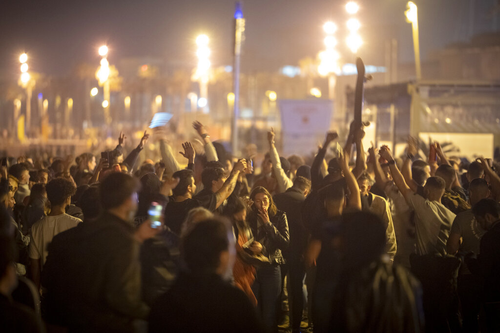 Gente bailando en una multitud en la playa de Barcelona, España, el domingo 9 de mayo de 2021. Celebraciones improvisadas tomaron las calles en distintos lugares de España cuando llegó la medianoche del sábado y expiró el estado de alarma de seis meses para contener los contagios de coronavirus, lo que levantó los toques de queda en muchas regiones. (AP foto/Emilio Morenatti)