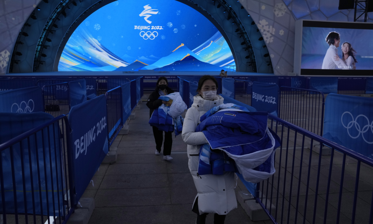 Staff members labor during a rehearsal of a victory ceremony at the Beijing Medals Plaza of the Winter Olympics in Beijing, China, Monday, Jan. 3, 2022. (AP Photo/Ng Han Guan)