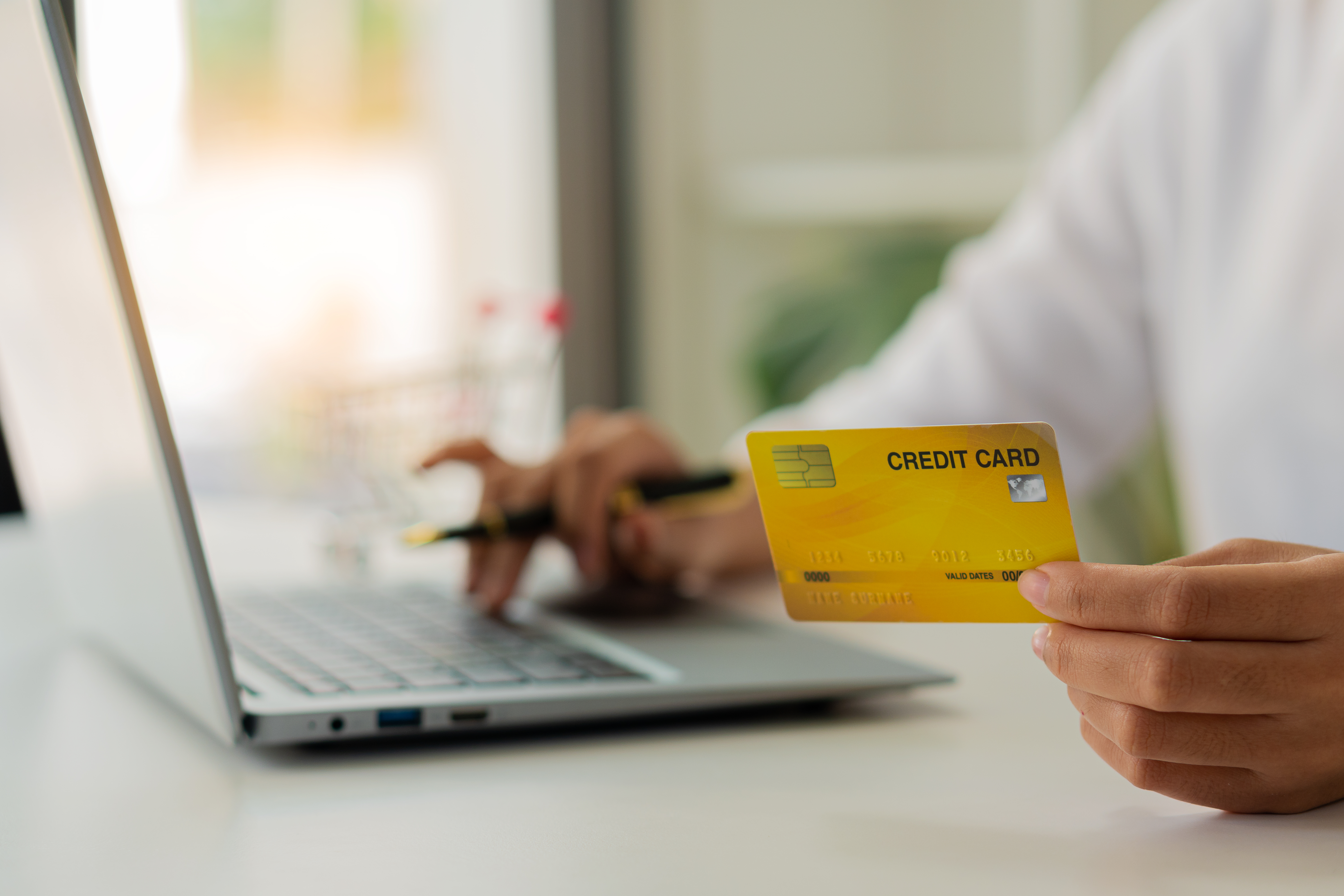 Young woman holding credit card and using laptop computer to work E-commerce Internet banking spending money Online product purchases, register via credit card to shop online.