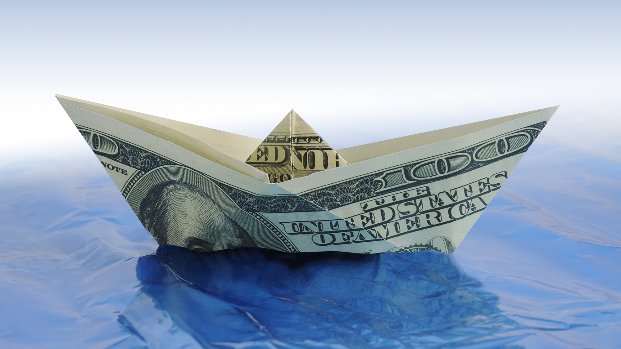 Barco de dólar de papel en el agua