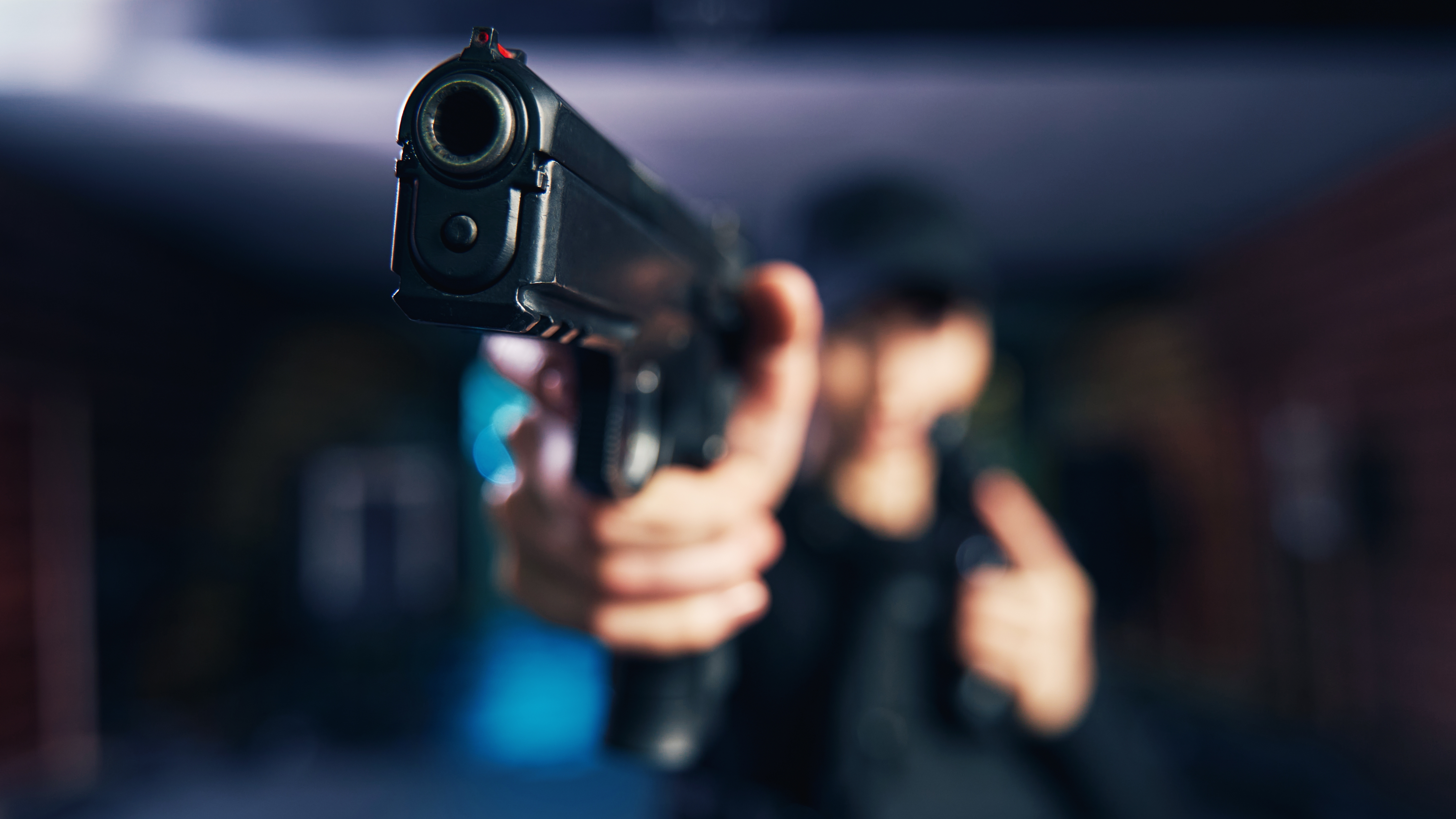 Foto borrosa de un militar caucásico experimentado vestido con uniforme negro sosteniendo la pistola con una mano robo