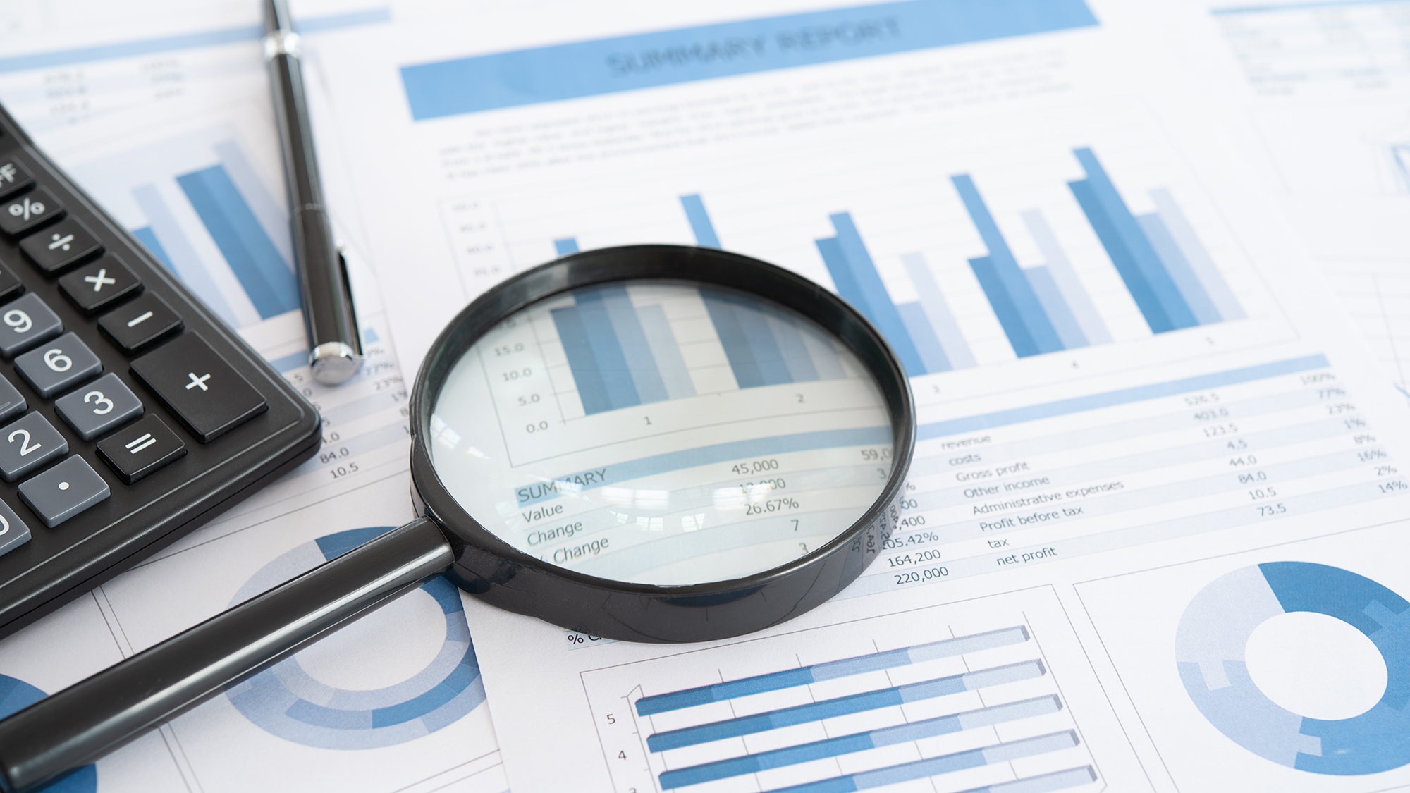 planificación de negocios e inversiones. Lupa con informe comercial en el escritorio del asesor financiero. Concepto de análisis de datos, contabilidad, auditoría, investigación empresarial.