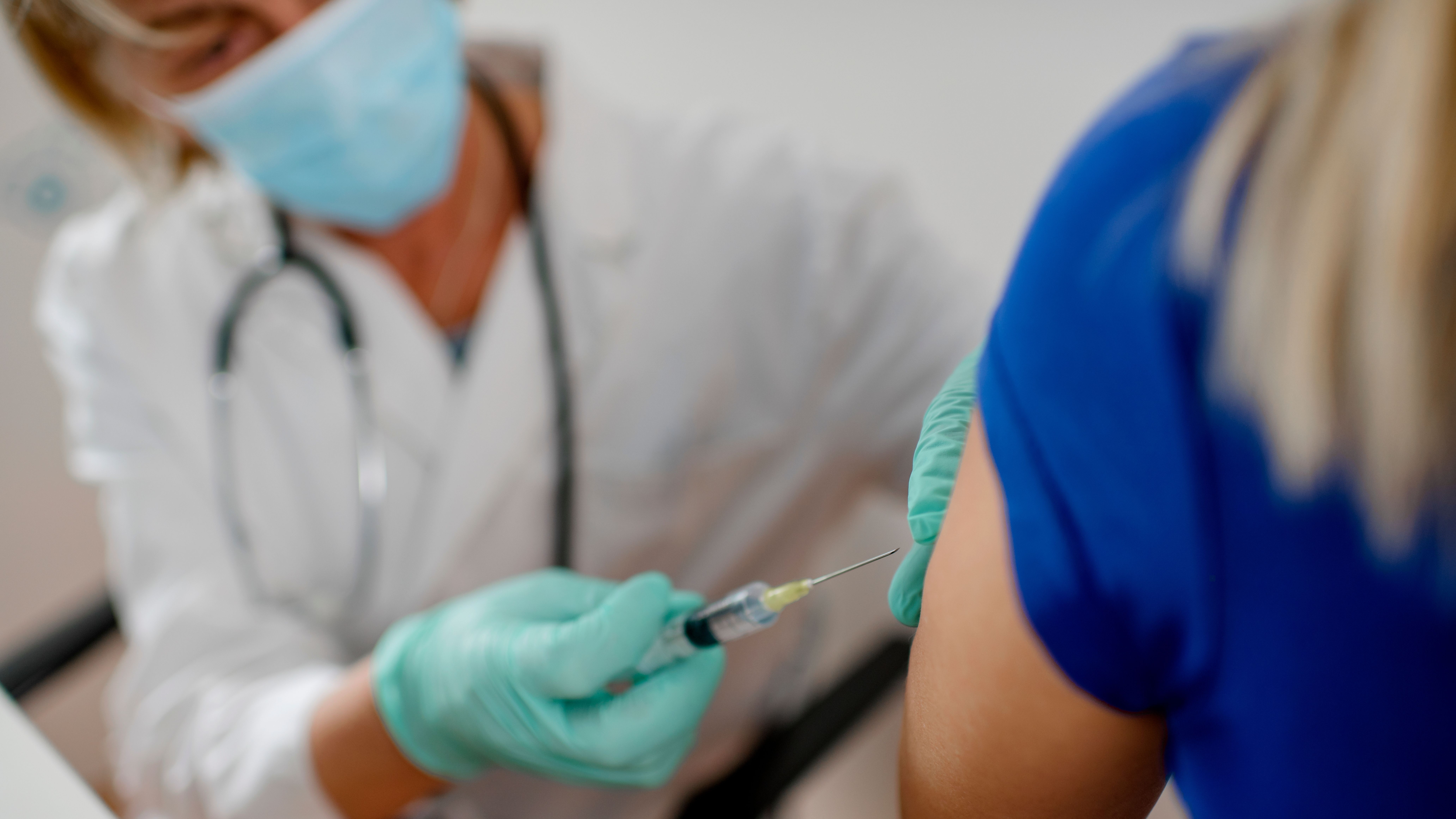 El primer plano del médico vacuna a la mujer. Llevan mascarillas protectoras.