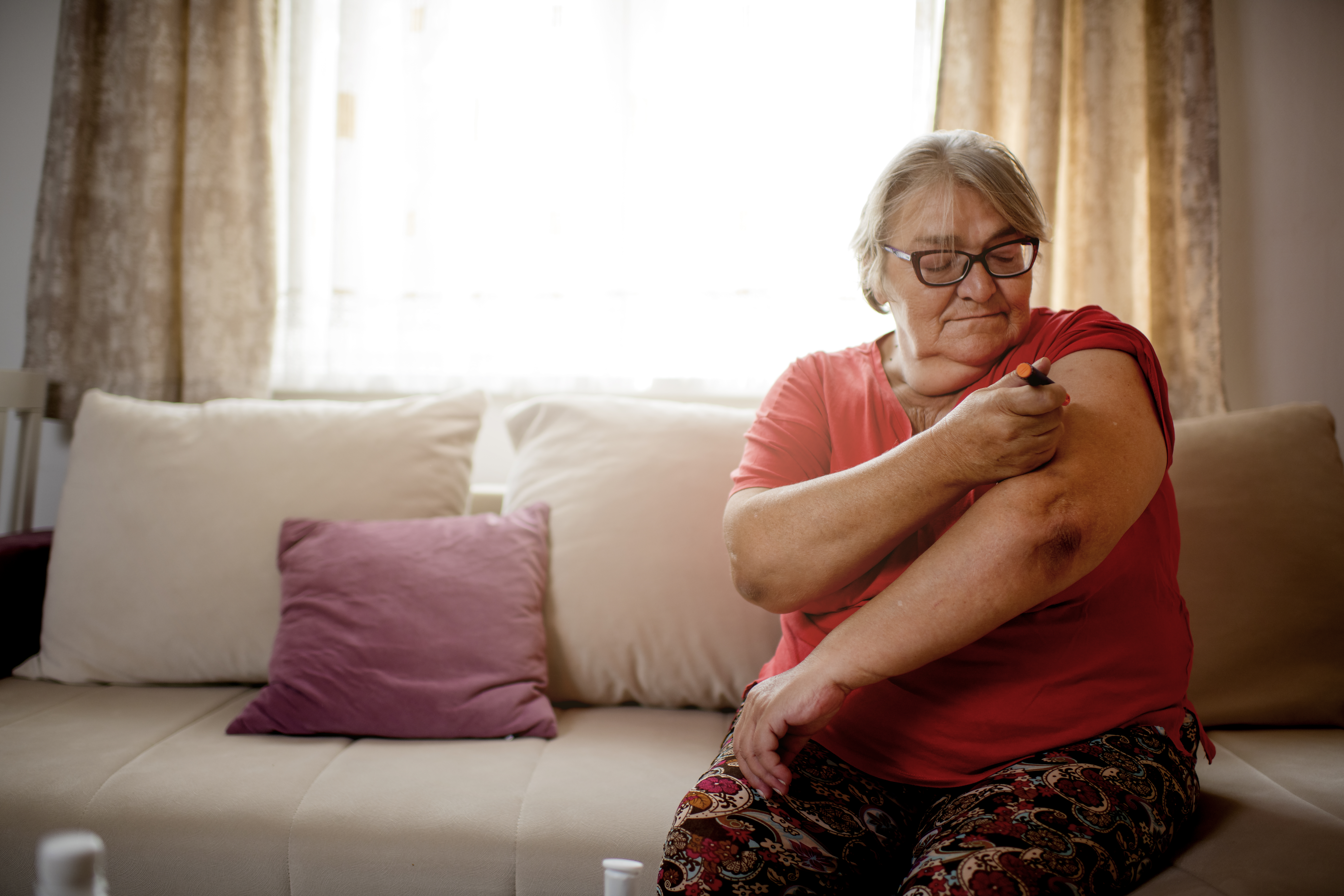 Senior mujer caucásica inyectando insulina en el brazo de ella en casa