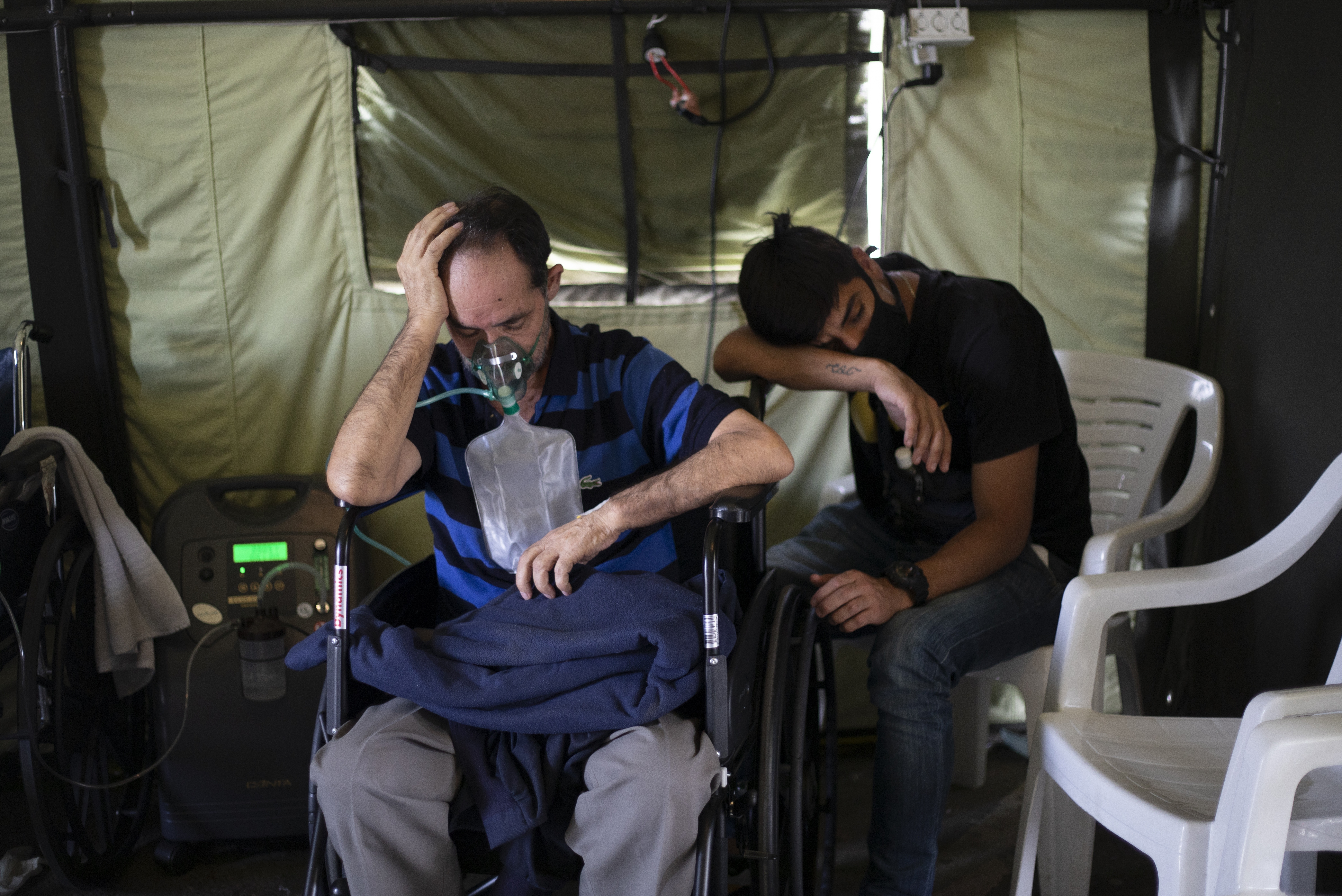 Pacientes contagiados con COVID-19 aguardan el domingo 21 de marzo de 2021 en un hospital de campaña erigido en el estacionamiento del auditorio Poliedro de Caracas, Venezuela. (AP Foto/Ariana Cubillos)