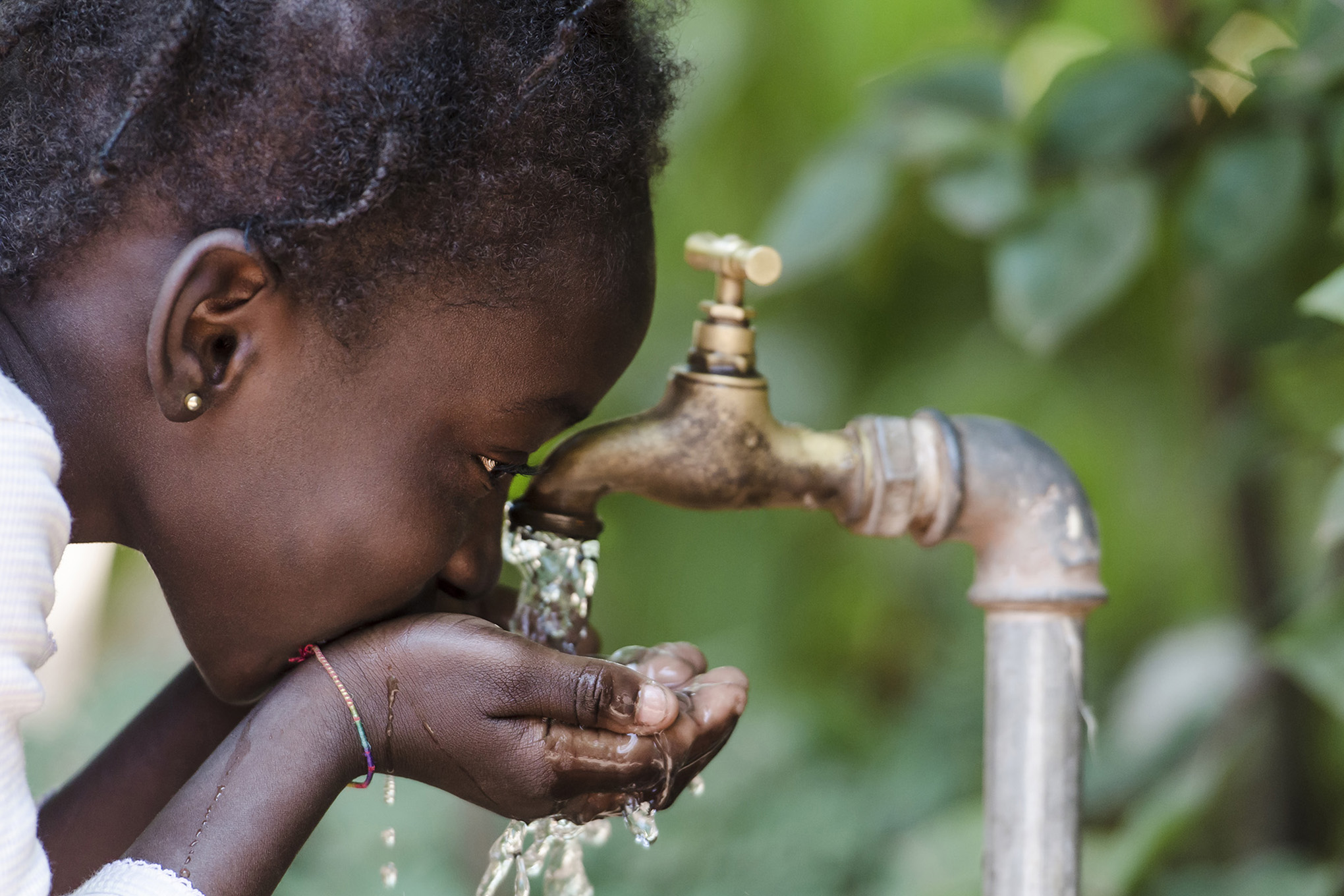 Niña africana bebiendo agua limpia de un grifo. Manos ahuecadas de un niño africano con agua saliendo de un grifo en las calles de la ciudad africana de Bamako, Malí.