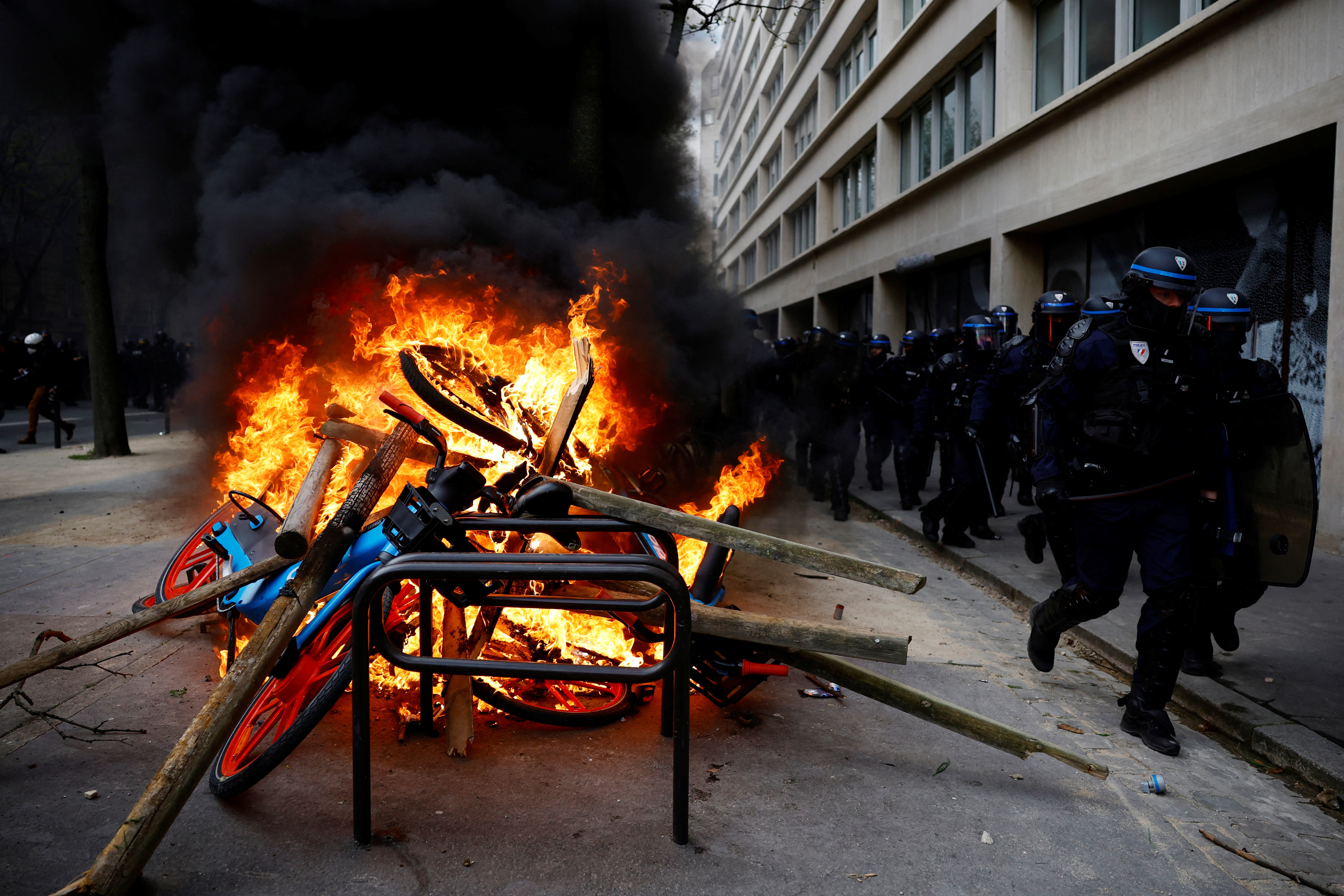 French CRS riot police run past objects on fire amid clashes with protesters at a demonstration as part of the eleventh day of nationwide strikes and protests against French government's pension reform, in Paris, France, April 6, 2023.   REUTERS/Sarah Meyssonnier