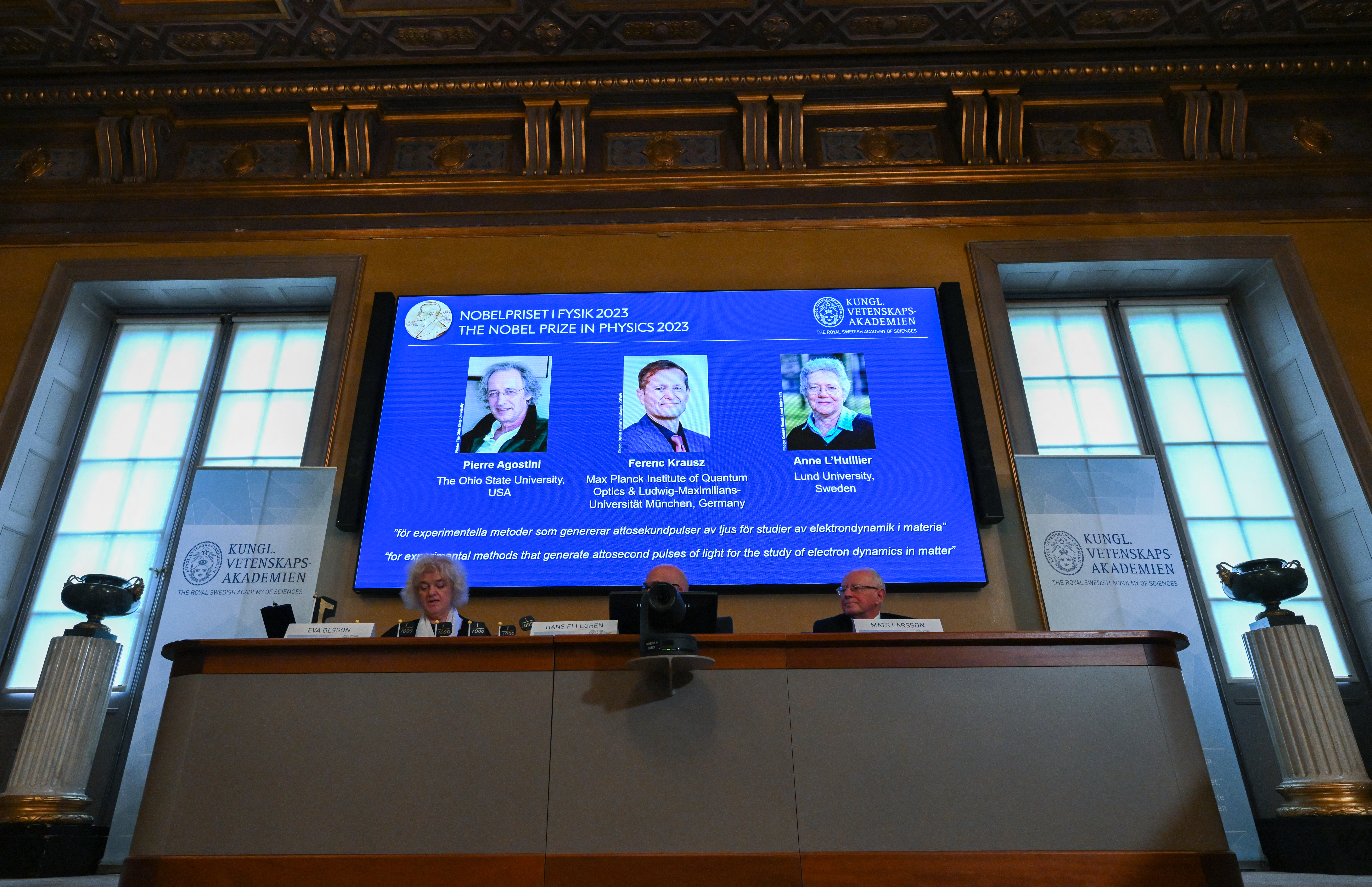 (L-R) A screen shows this year's laureates US-based physicist Pierre Agostini, Hungarian-Austrian physicist and French physicist Anne L�Huillier during the announcement of the winners of the 2023 Nobel Prize in Physics at Royal Swedish Academy of Sciences in Stockholm on October 3, 2023. (Photo by Jonathan NACKSTRAND / AFP)