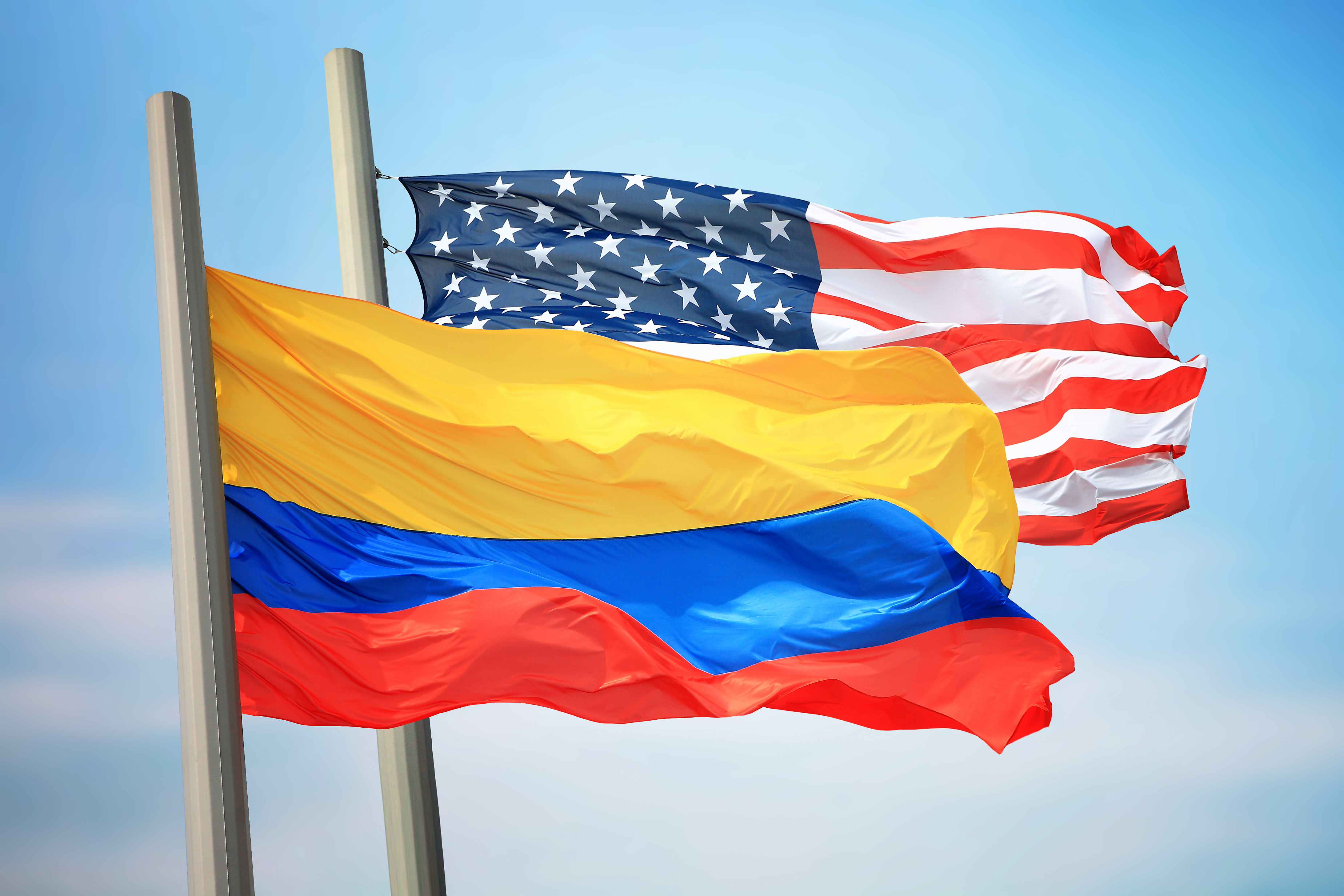 Flags of Colombia and the USA against the background of the blue sky