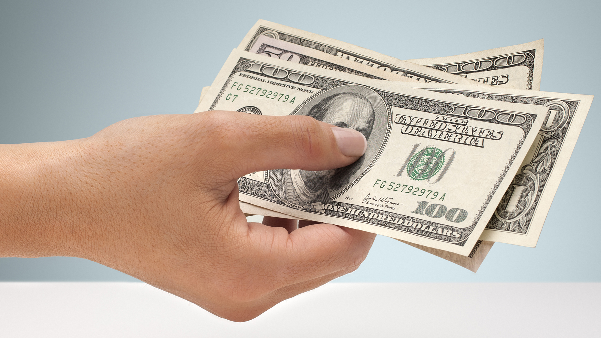 Mano sosteniendo una selección de billetes de dólar estadounidense