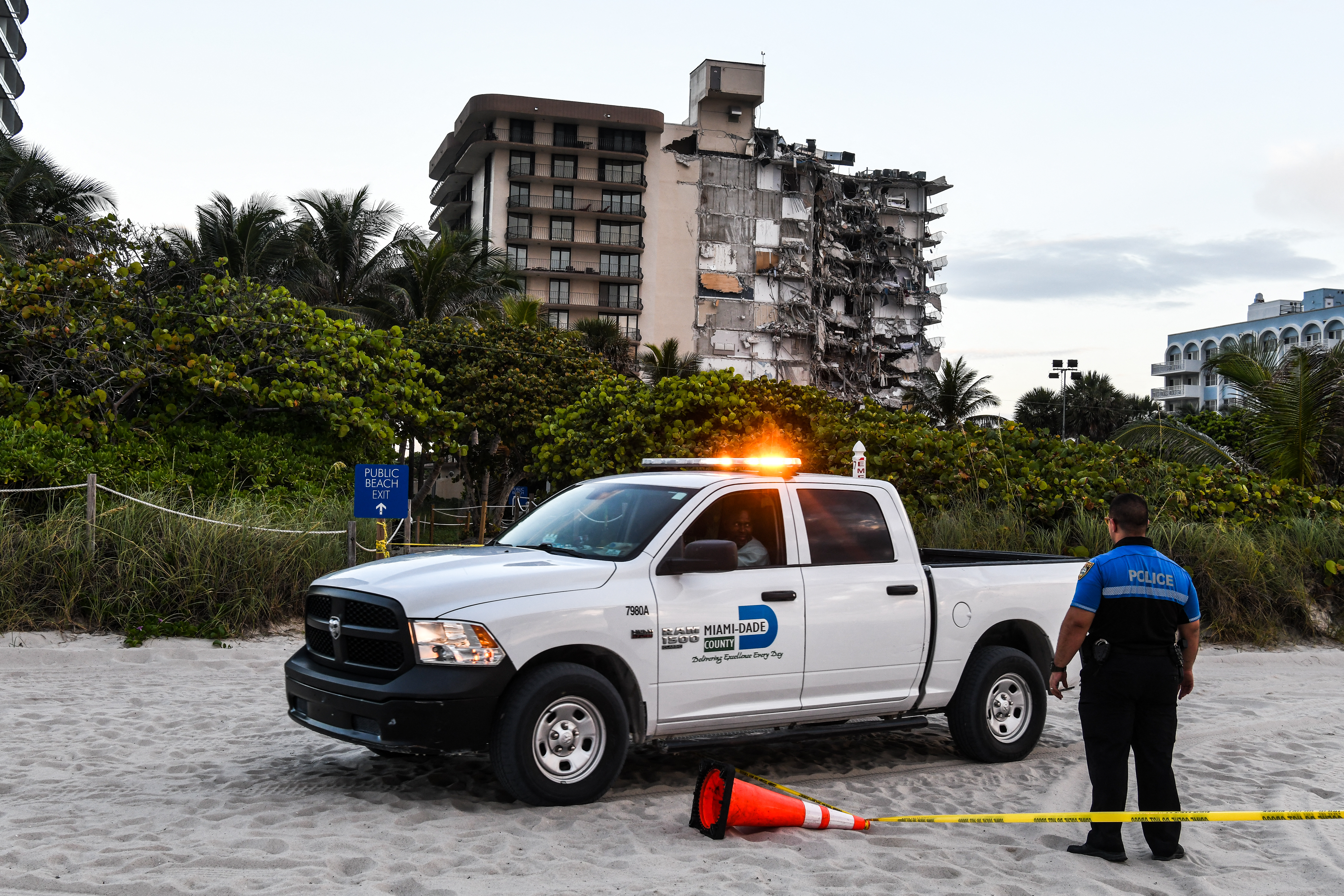 Police stand guard near a partially collapsed building a partially collapsed building in Surfside north of Miami Beach, on June 24, 2021. - The multi-story apartment block in Florida partially collapsed early June 24, sparking a major emergency response. Surfside Mayor Charles Burkett told NBC�s Today show: �My police chief has told me that we transported two people to the hospital this morning at least and one has died. We treated ten people on the site.� (Photo by CHANDAN KHANNA / AFP)