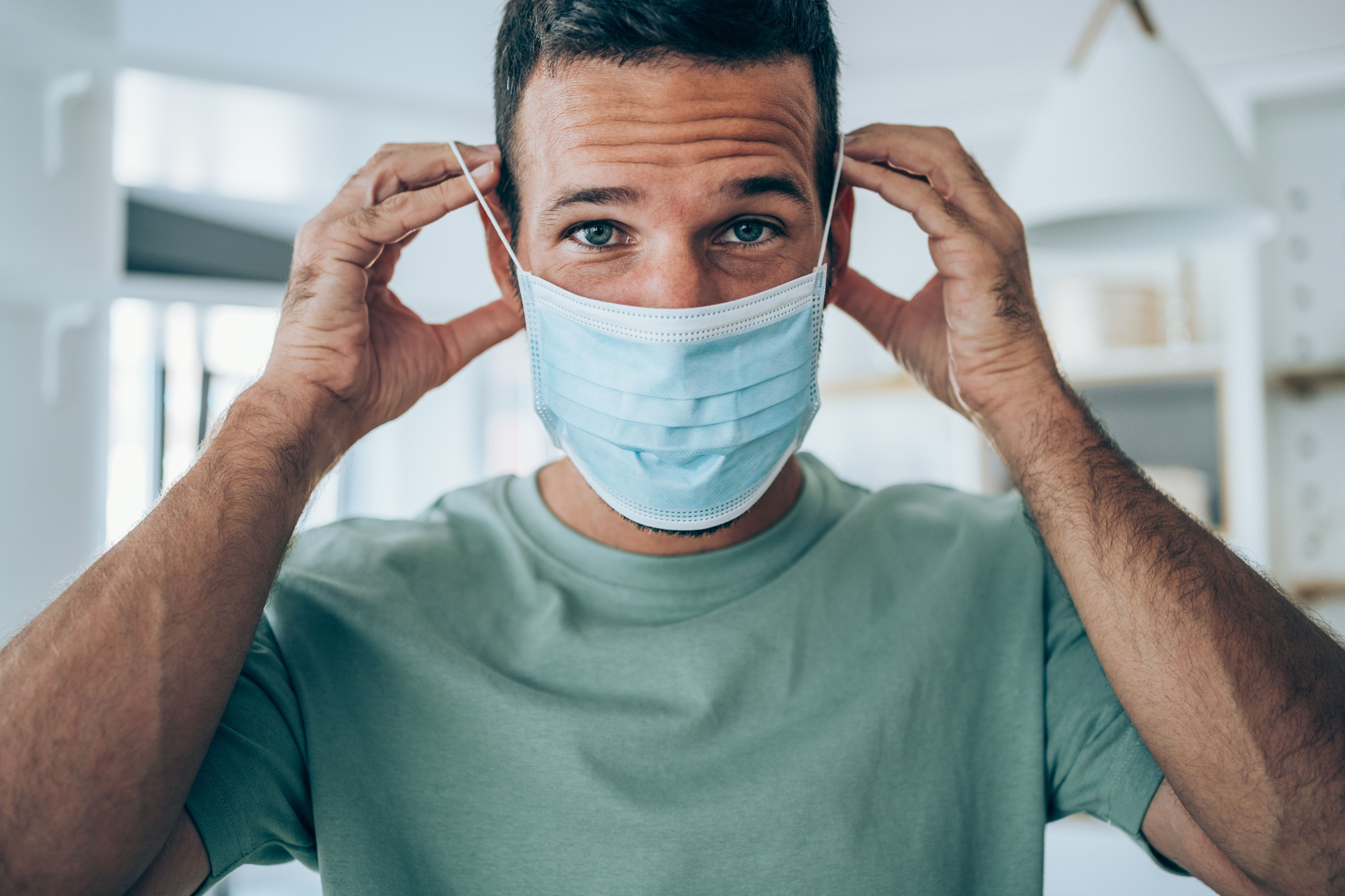 Apuesto joven poniéndose una máscara protectora para la prevención contra virus.