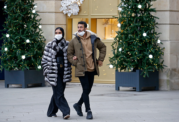 PARIS, FRANCE - DECEMBER 16: People wearing protective face masks walk past decorated Christmas trees at 'Place Vendome' during the coronavirus (COVID-19) epidemic on December 16, 2021 in Paris, France. The wave of Covid-19 continues in France, the number of contaminations registering Wednesday at its highest level since the spring and hospitalizations continuing to increase, according to daily data from Public Health France. As a result, the French government announced Thursday to restore, from Saturday, the obligation of "compelling reasons" for travelers leaving or returning from the United Kingdom in the face of "the extremely rapid distribution of the Omicron variant" in this country. French President Emmanuel Macron announced in a television interview last night that he would not rule out having compulsory vaccination against COVID-19 one day. (Photo by Chesnot/Getty Images)