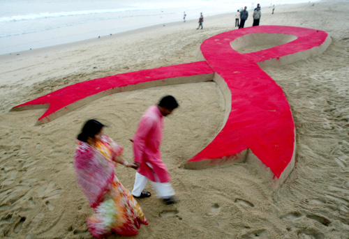 Un joven indio pasa a unos metros de una escultura de arena creada por Sudarshan Pattnaik en el día internacional del SIDA en Puri, India 